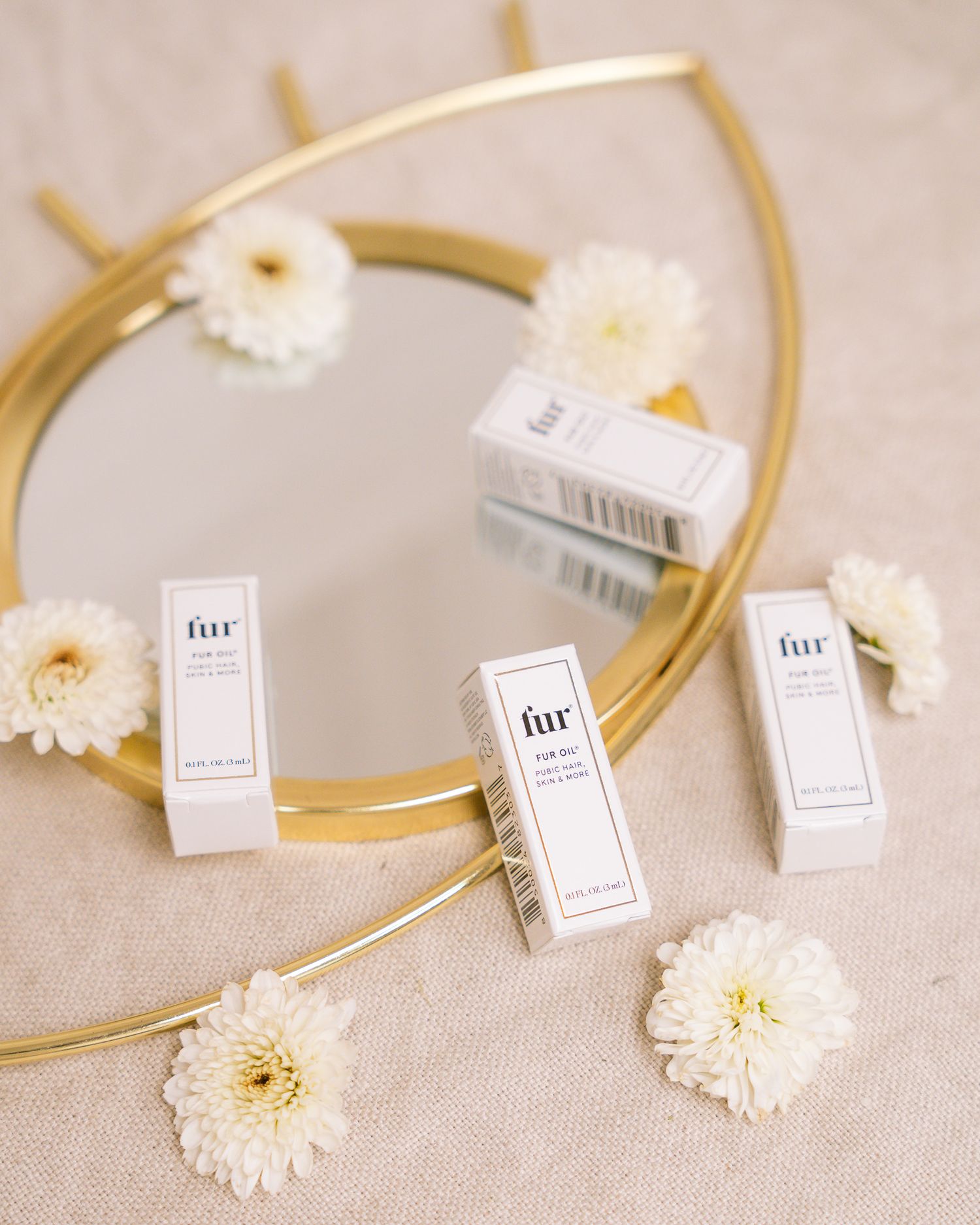 Small white product boxes arranged with gold circular frame and white flowers.
