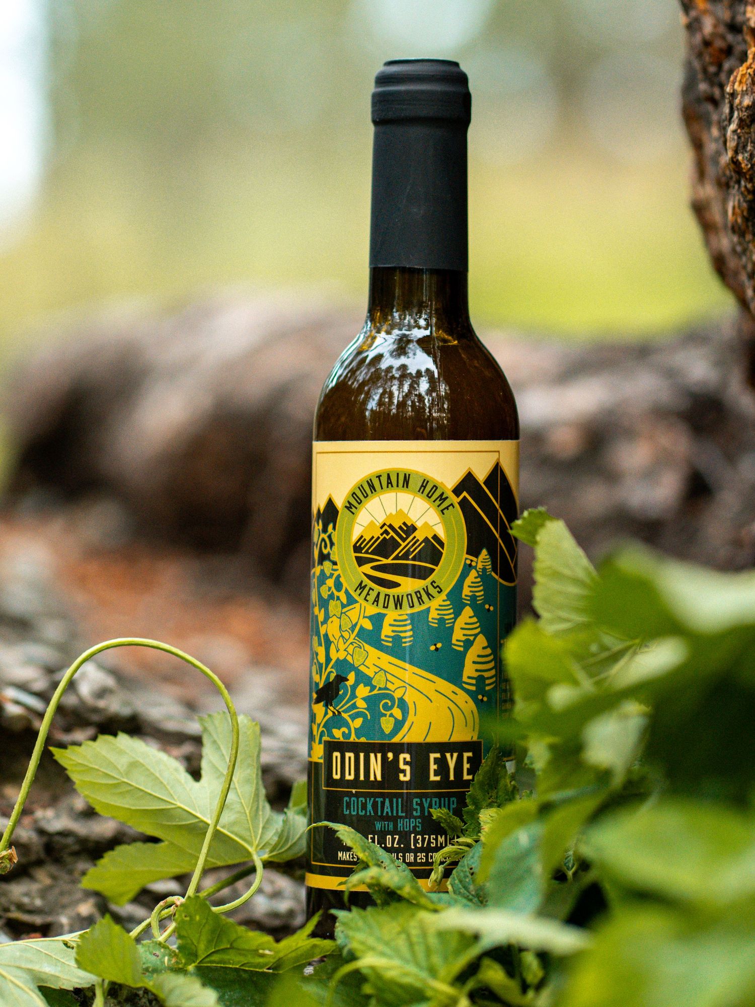 Bottle of Lion's Eye liqueur photographed among green leaves in natural outdoor setting.