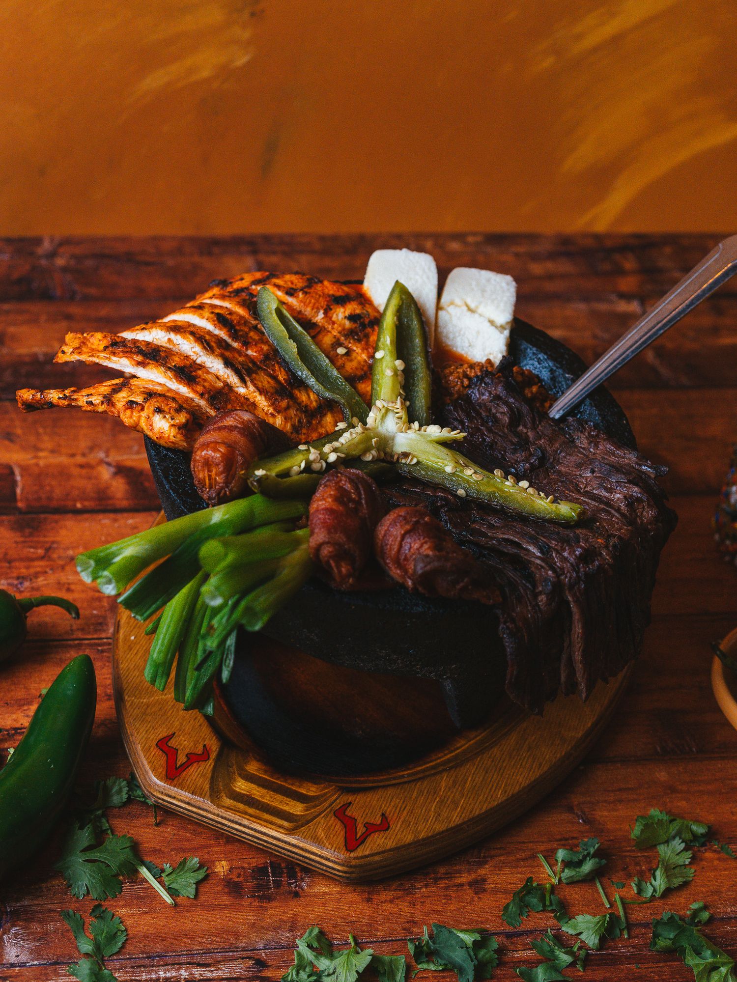 Grilled meats and vegetables served on a rustic wooden table with fresh herbs.
