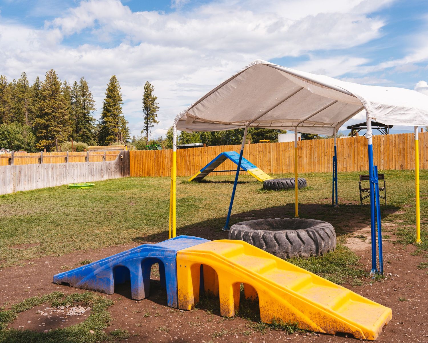 Colorful outdoor playground equipment with ramps and tunnels under a beige canopy.