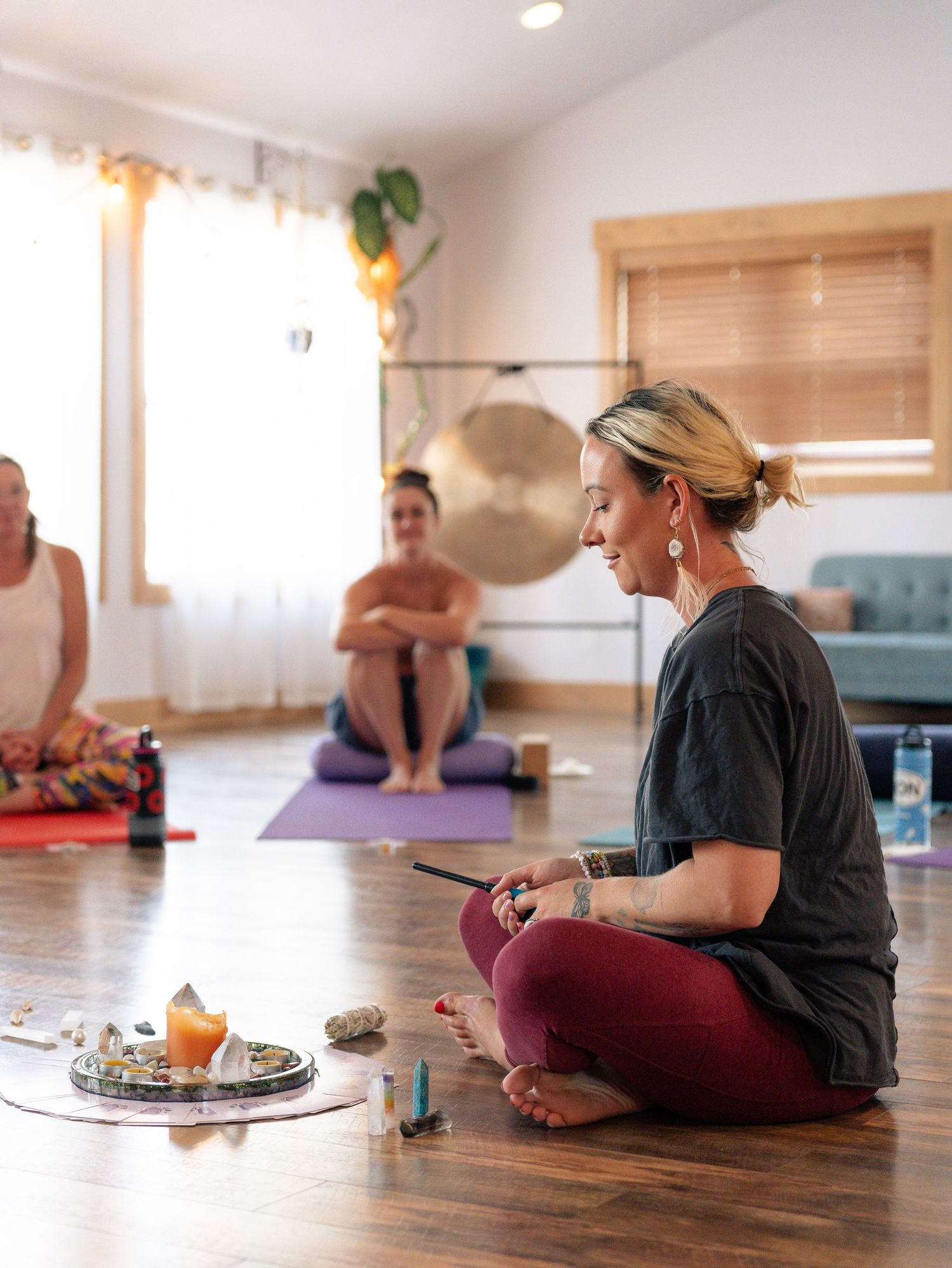 Meditation class setting with yoga mats, singing bowl, and natural light streaming through window.