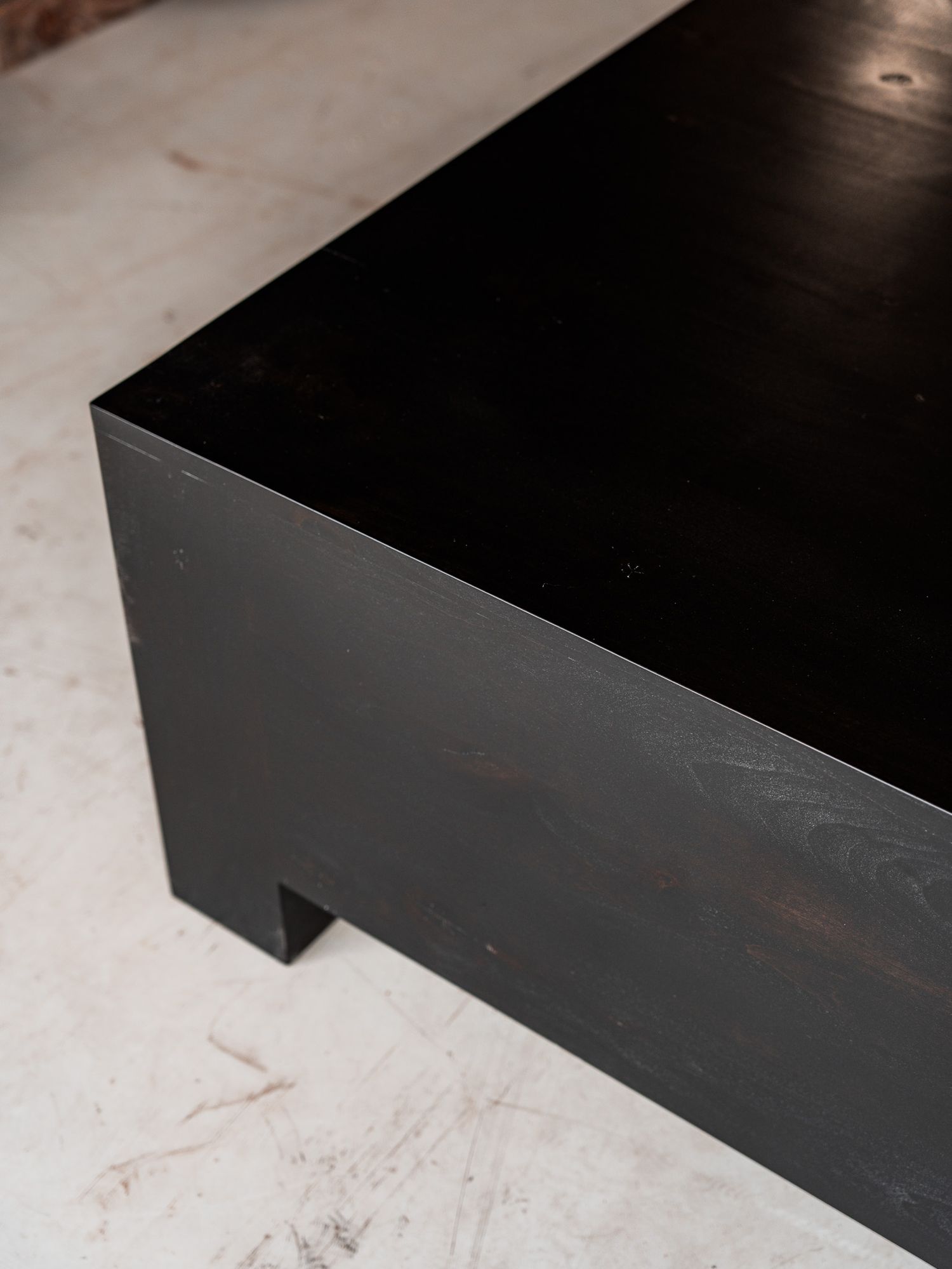 Multiple close-up shots show the corner edge profile of a black painted or stained furniture piece against a light surface.