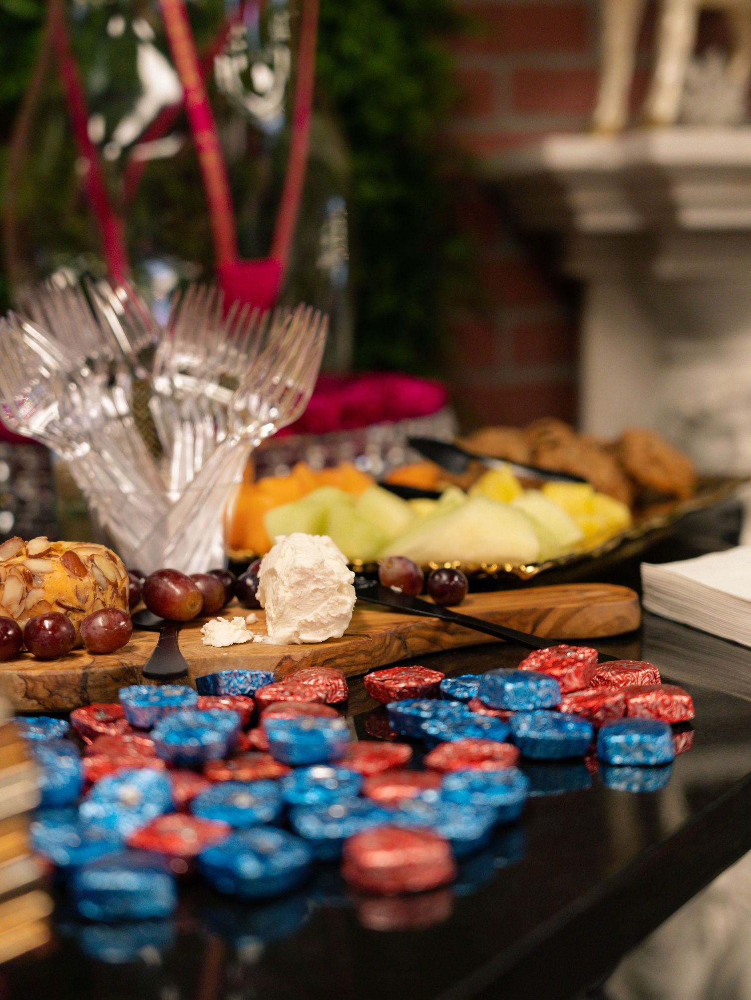 Colorful party spread with snacks and blue poker chips on dark table surface.