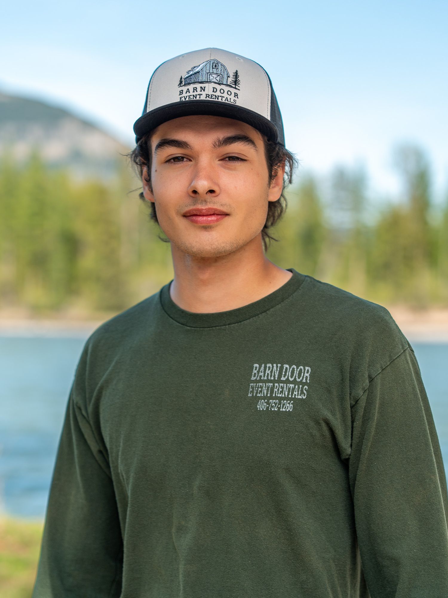 Casual outdoor portraits by a lake wearing a green shirt and baseball cap.