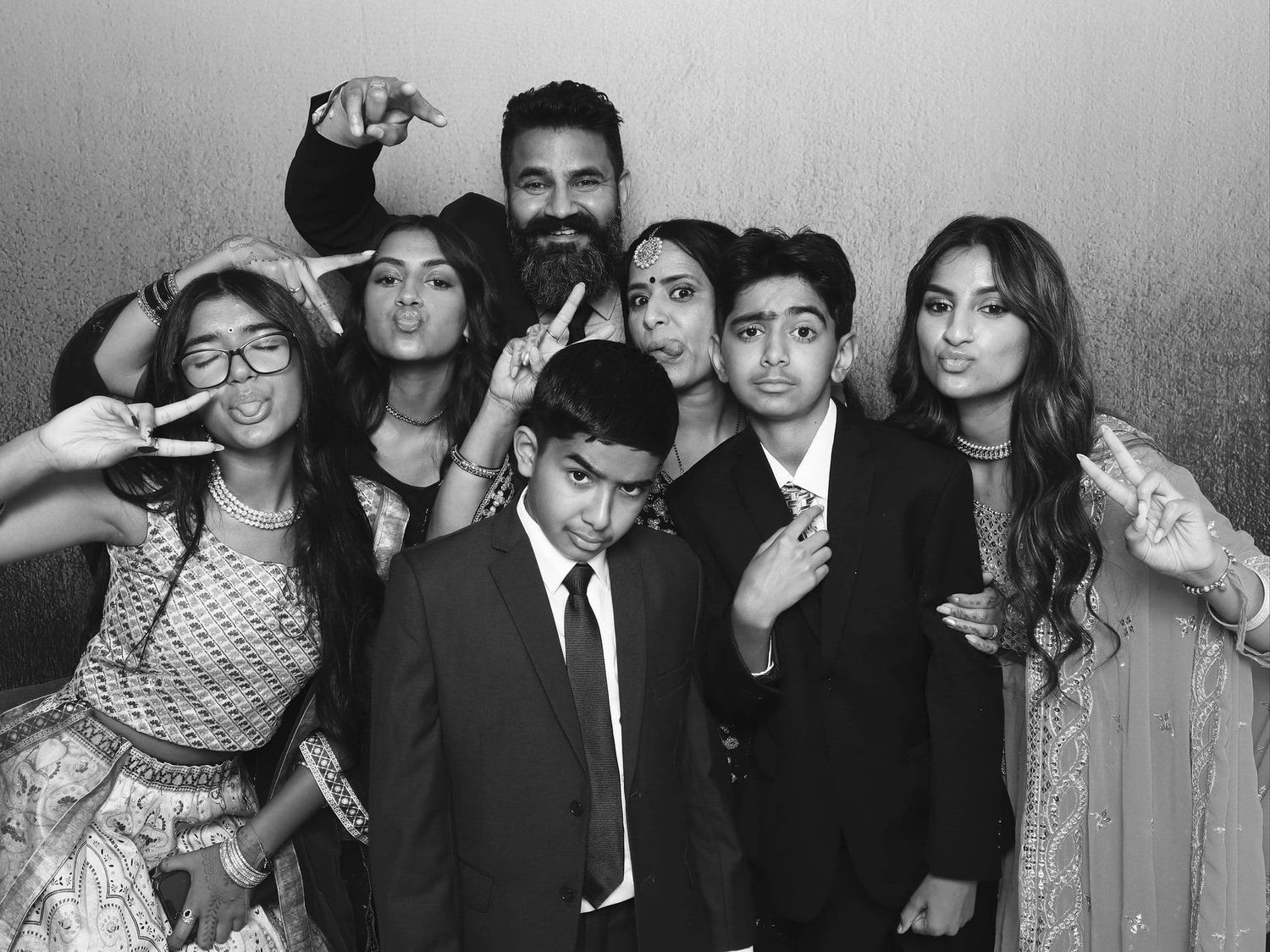 Black and white family photo booth picture with adults and children in formal wear.