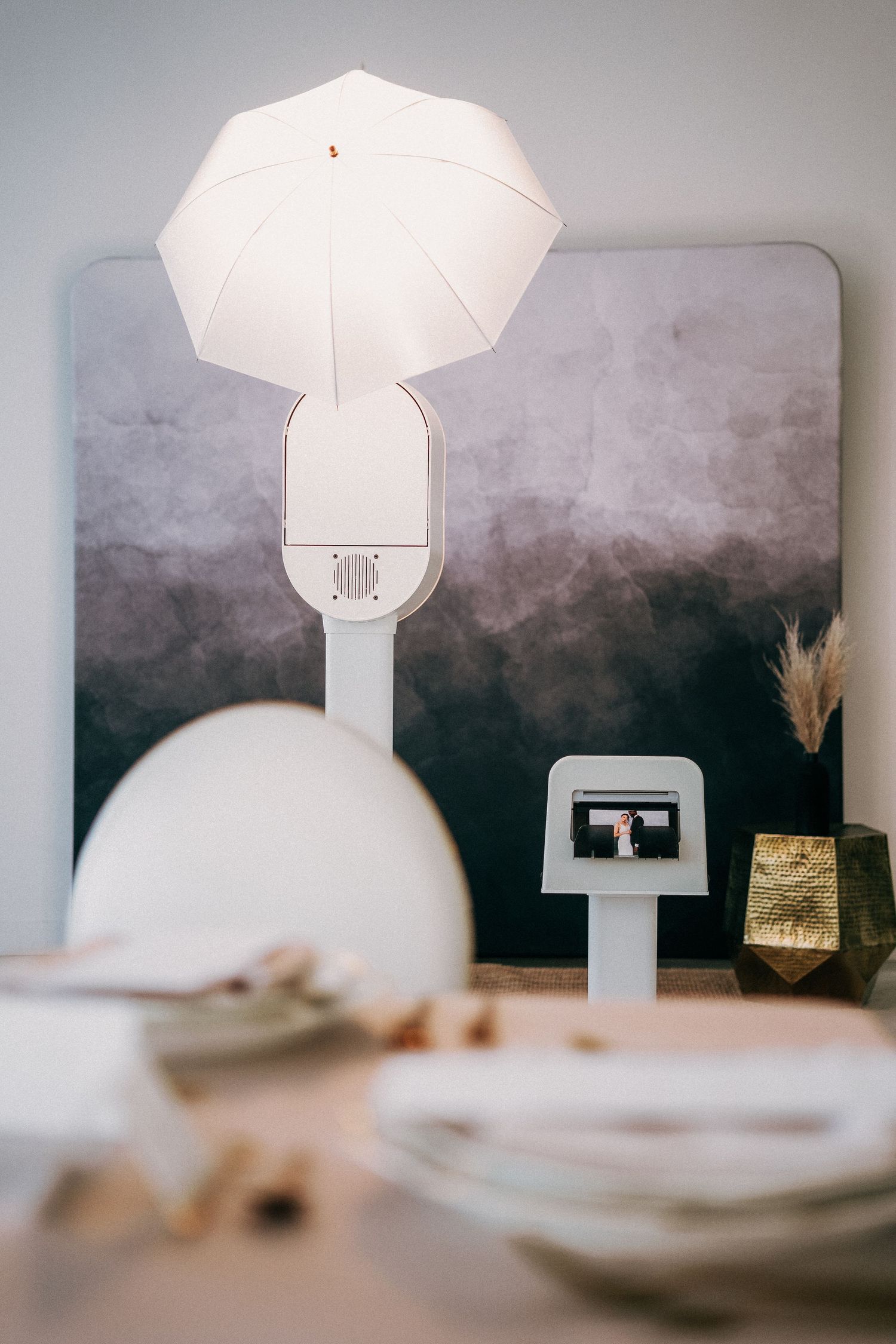 White umbrella shaped light fixture against a dark gray backdrop with decorative elements and dishes in the foreground.