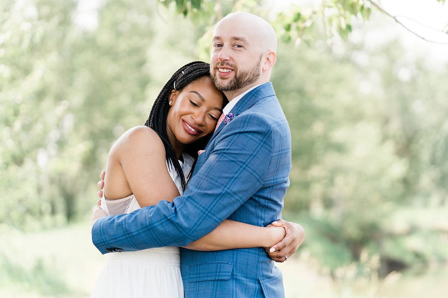 Happy interracial couple shares a warm embrace outdoors during their engagement photo session.