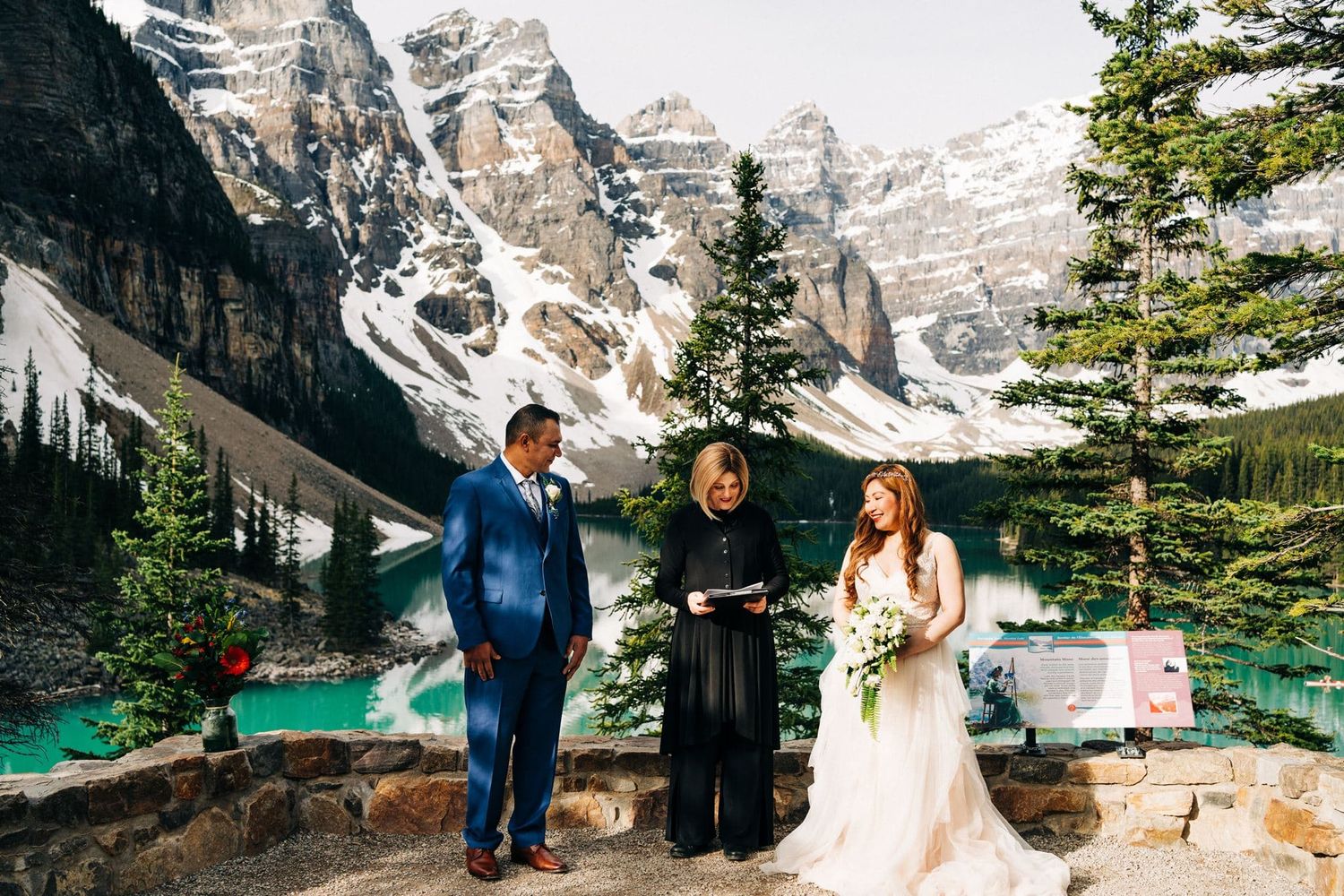 Couple exchanging vows at Moraine Lake elopement with turquoise water and Rocky Mountains backdrop in Banff.