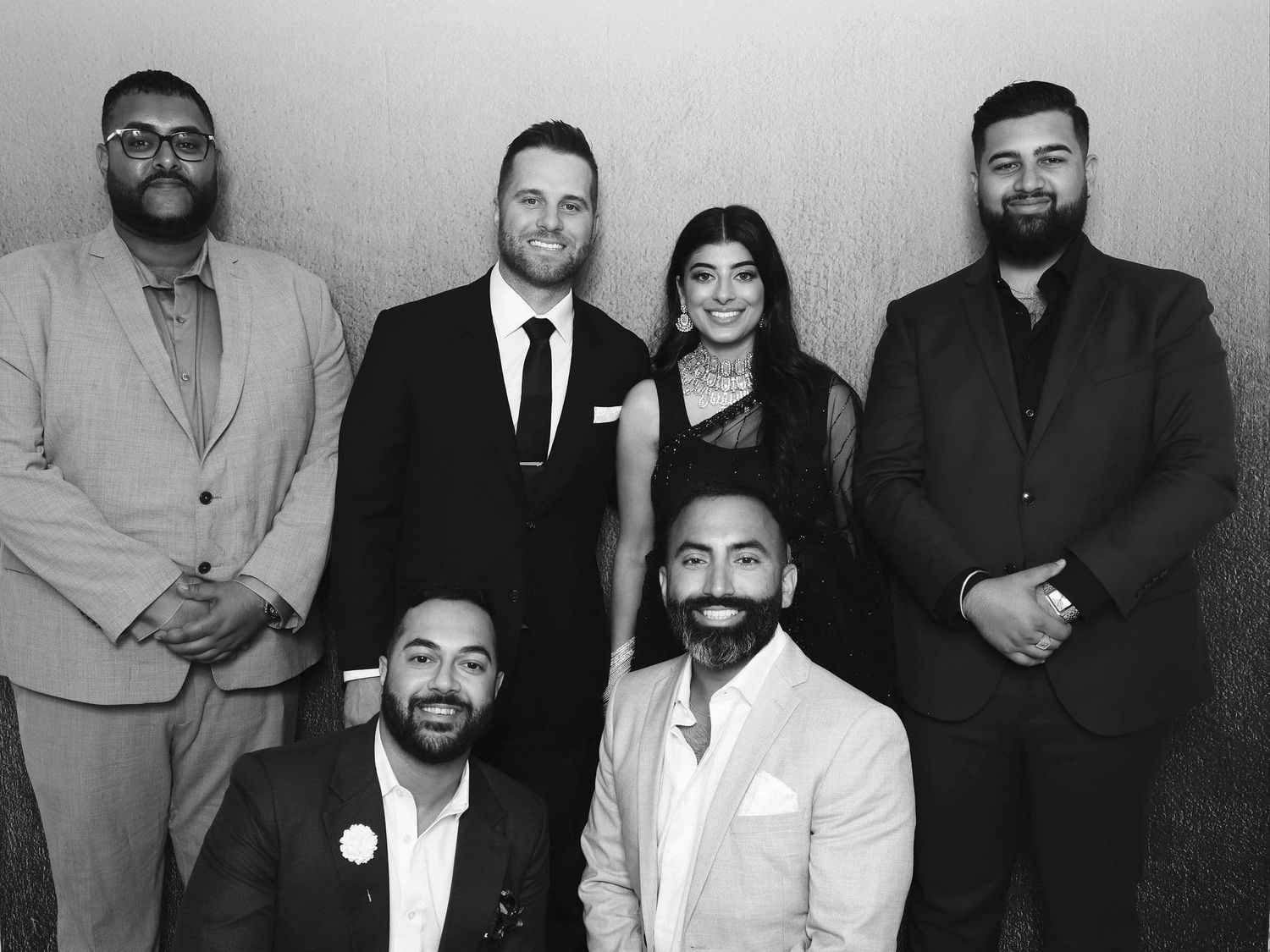 Black and white group photo of six formally dressed people posing together at an event.
