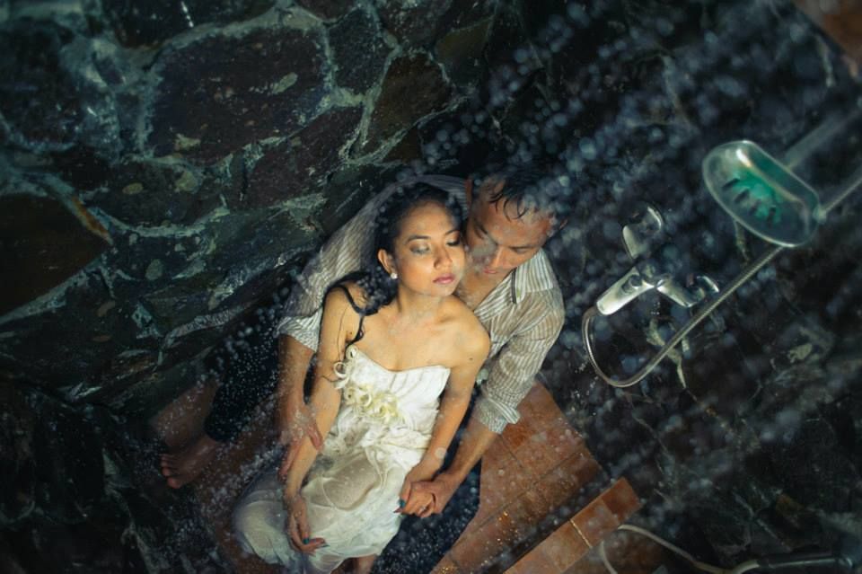 Couple embracing in a shower, viewed from above, with marble walls and water droplets around them.