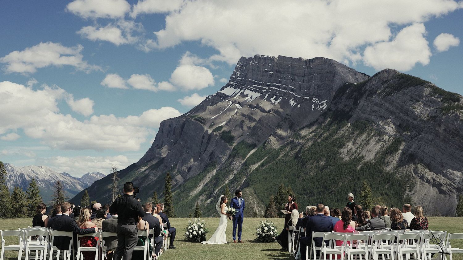 Outdoor wedding ceremony setup with white chairs facing scenic Mount Rundle in Banff National Park, Alberta.