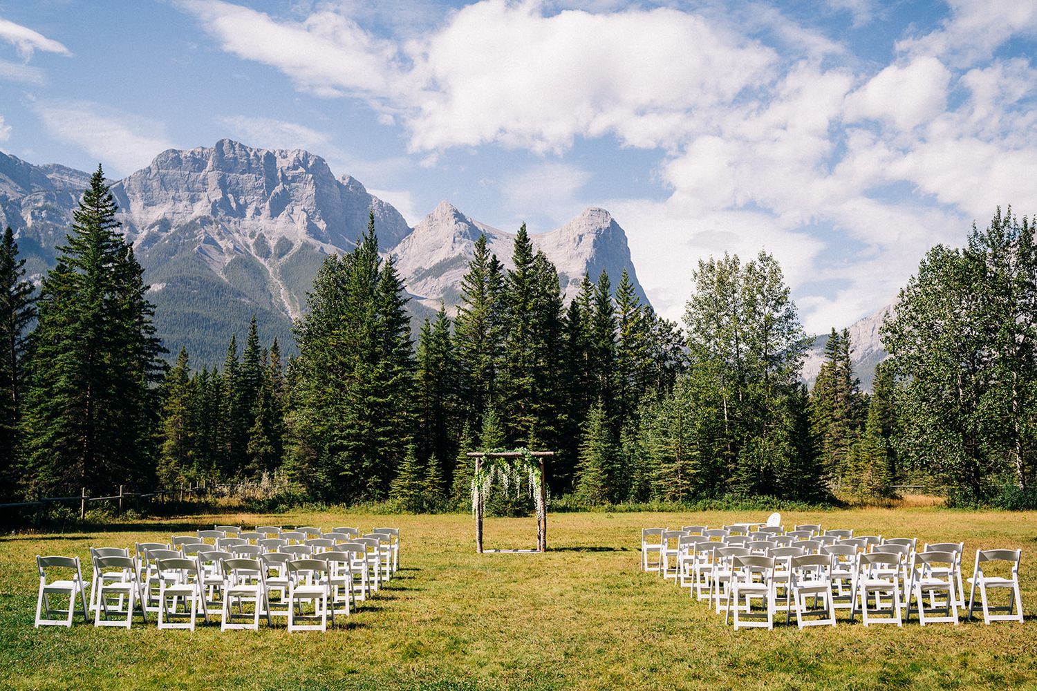 Panoramic mountain landscape with white chairs set up for an outdoor wedding ceremony.