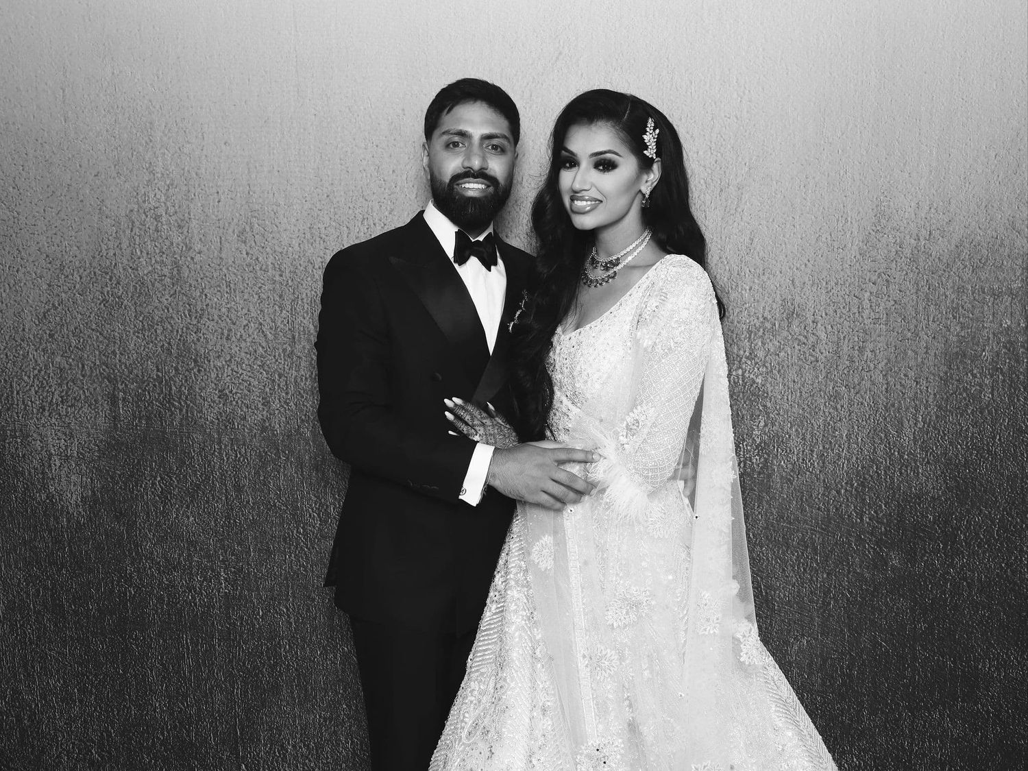 Elegant bride and groom posing for a classic black and white wedding portrait.
