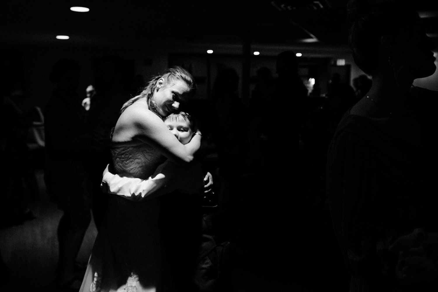 Black and white photo of a bride and groom sharing an emotional embrace on the dance floor at their wedding reception.