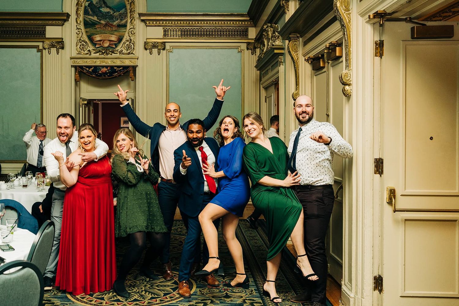 Group of friends posing and dancing at a formal event in an elegant ballroom venue.
