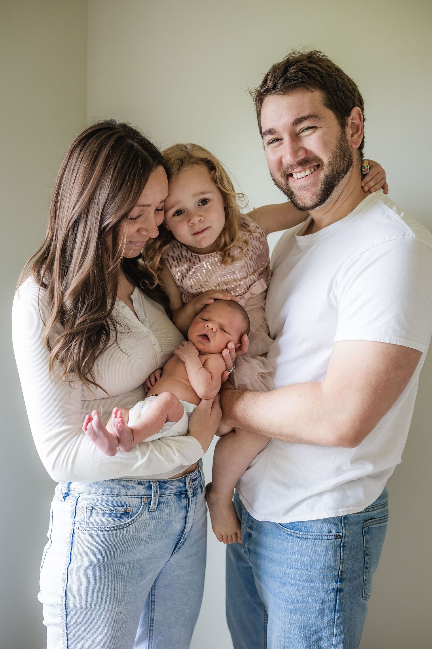 An intimate family portrait session with parents and child wearing coordinated white tops and denim.