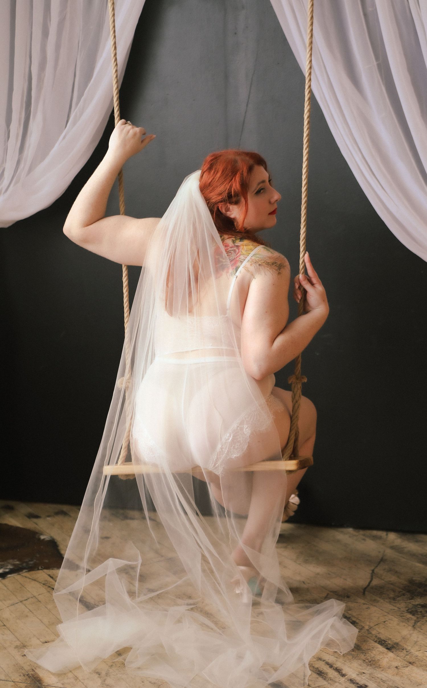 Artistic bridal portrait with flowing tulle veil against dark backdrop.