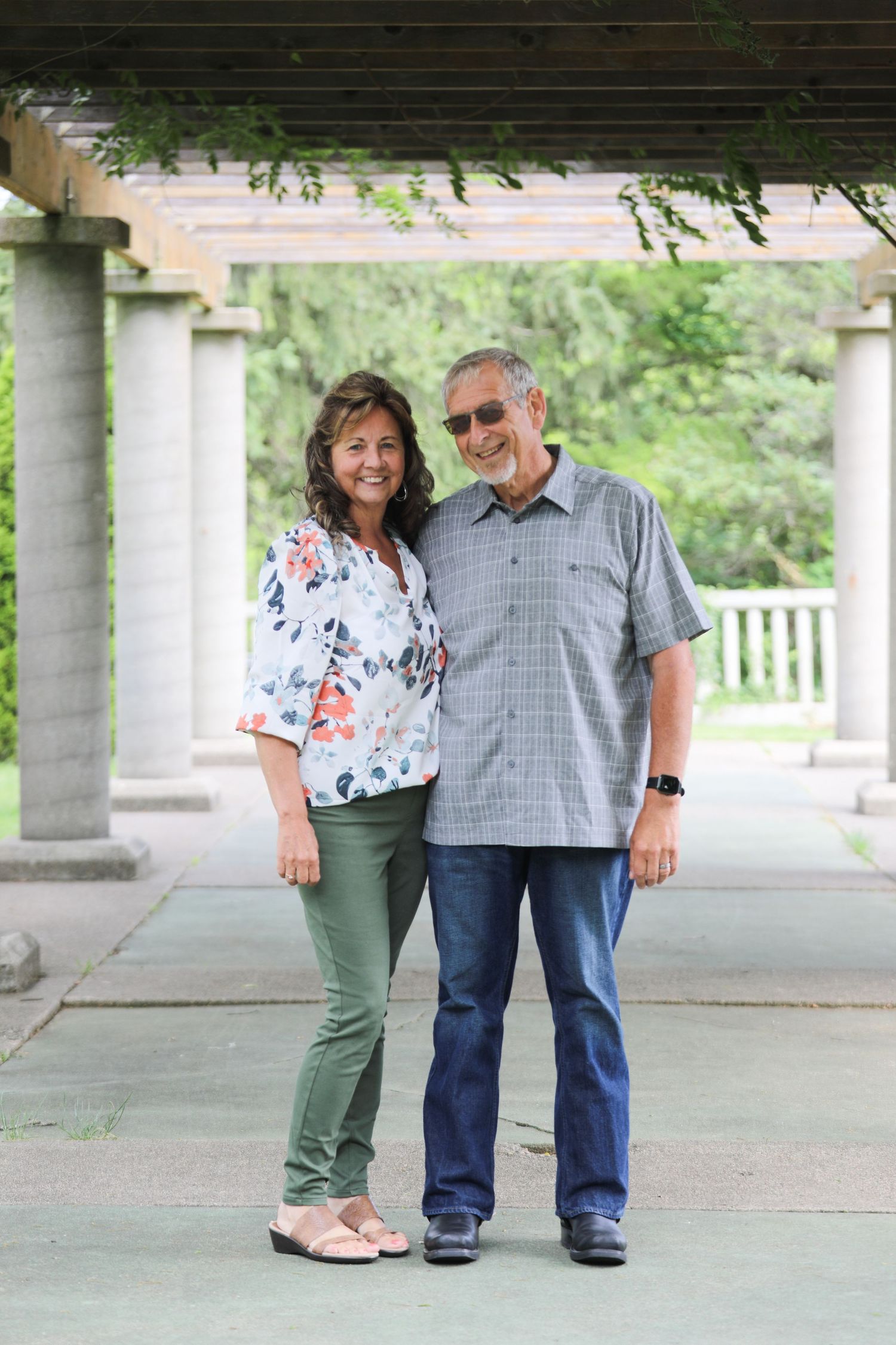 Couple posing under a covered walkway with white columns.