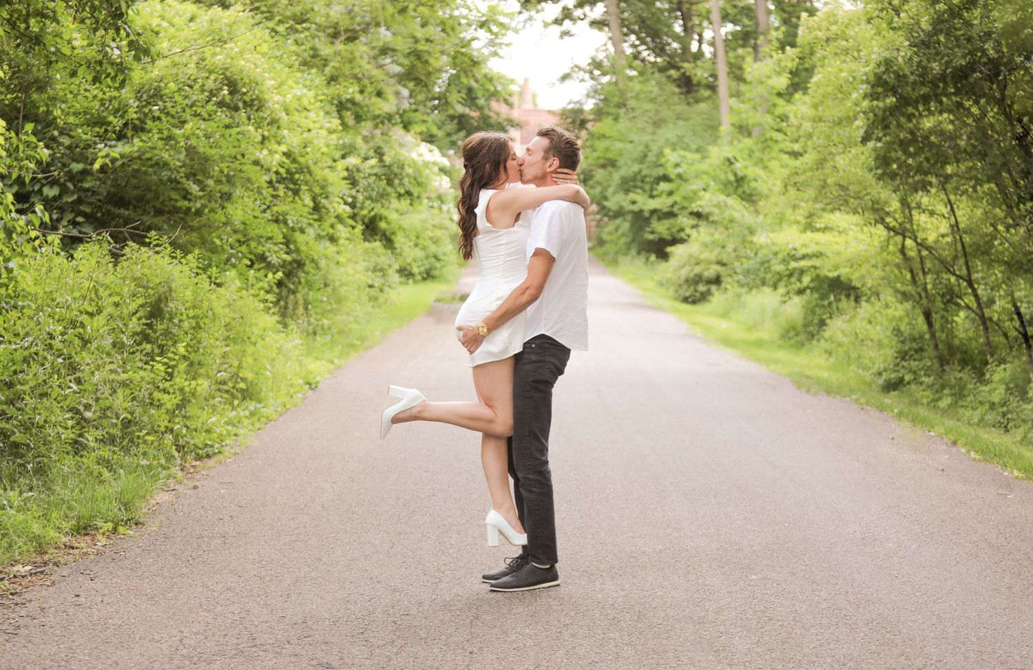 A joyful embrace on a tree-lined path during a sunny day.