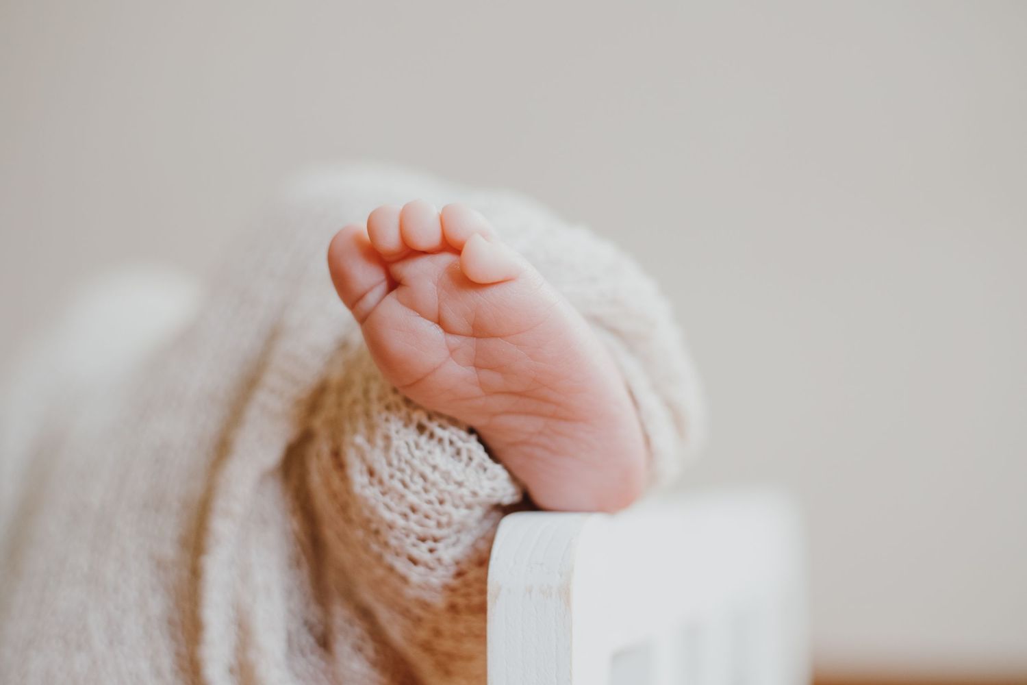 Close up of tiny baby's foot wrapped in soft white knit fabric.