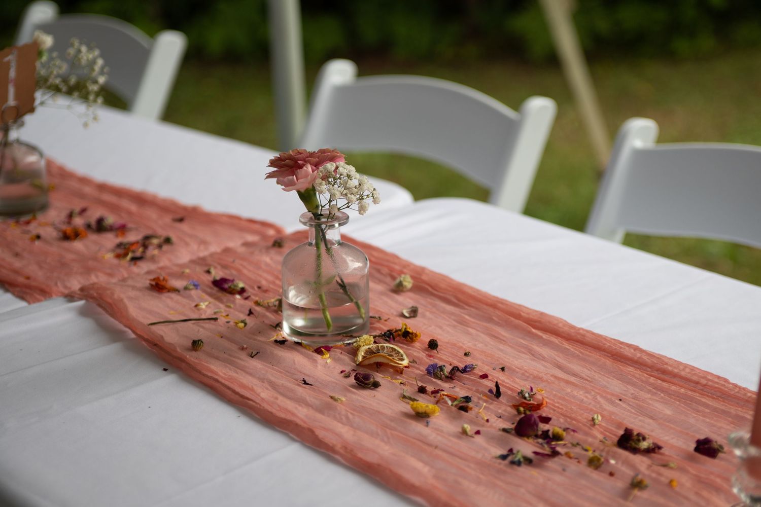 Wedding table setting with coral runner and scattered floral petals.