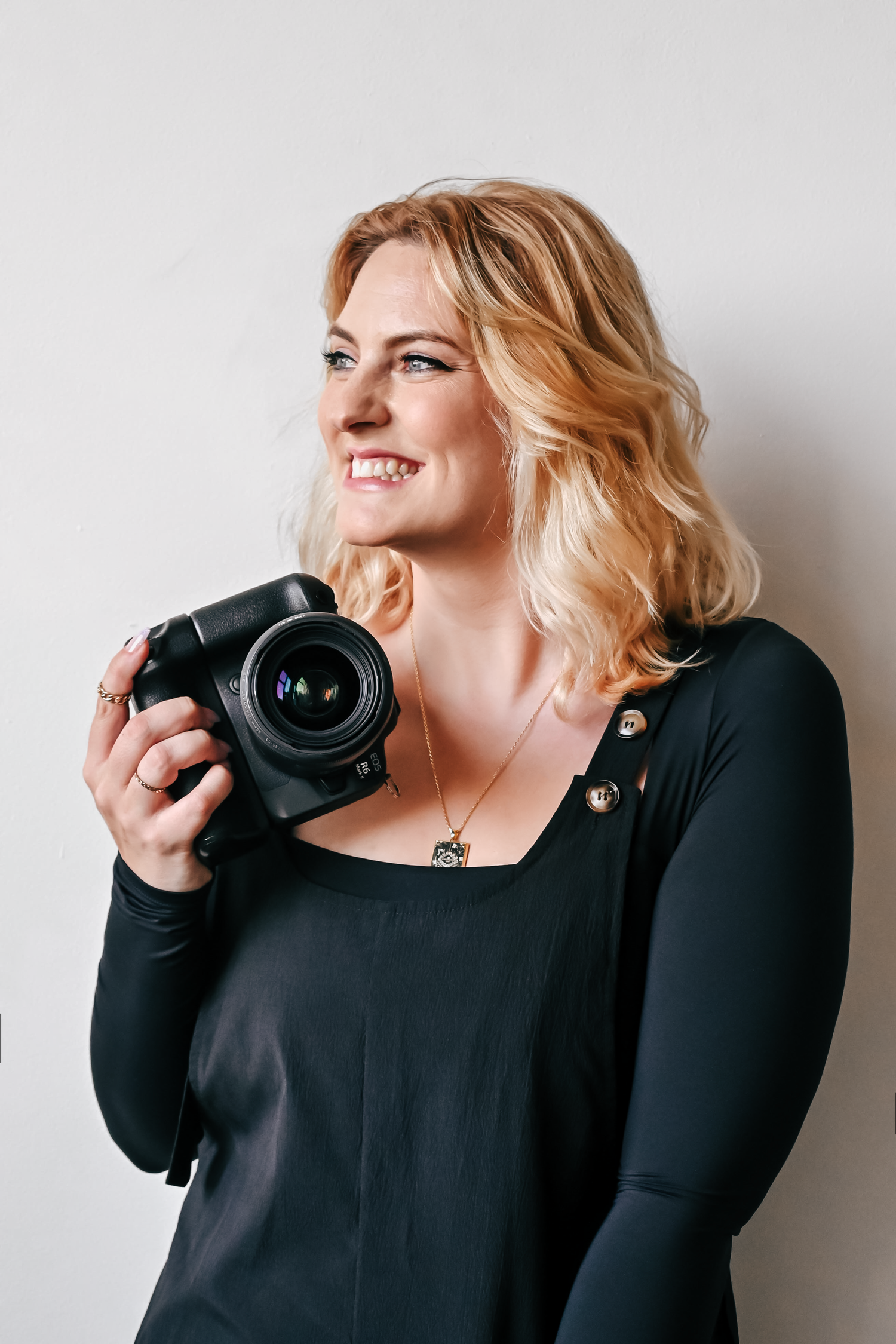 Professional photographer holding a camera against white background.