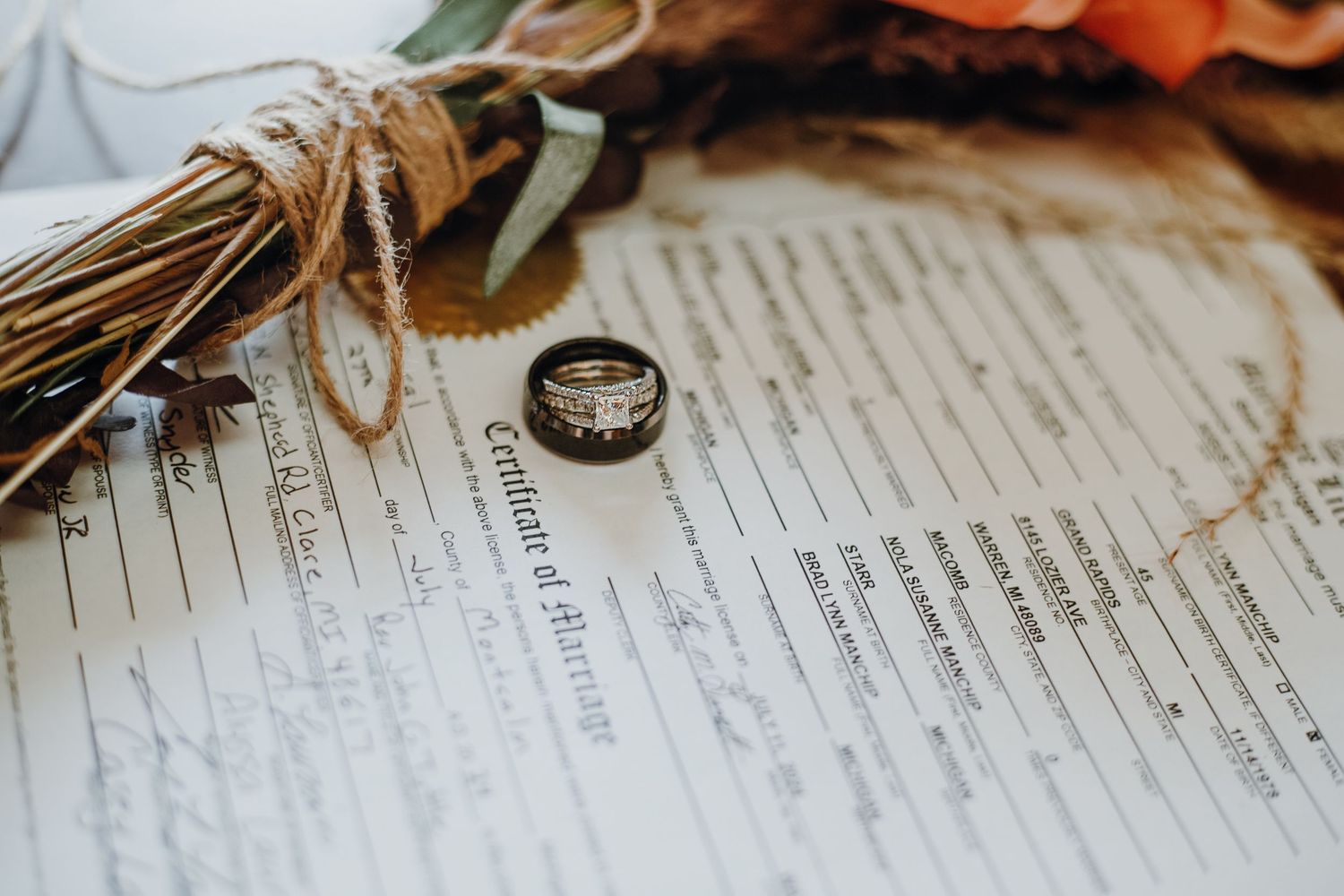 Close-up of wedding rings resting on official marriage documents with decorative elements.