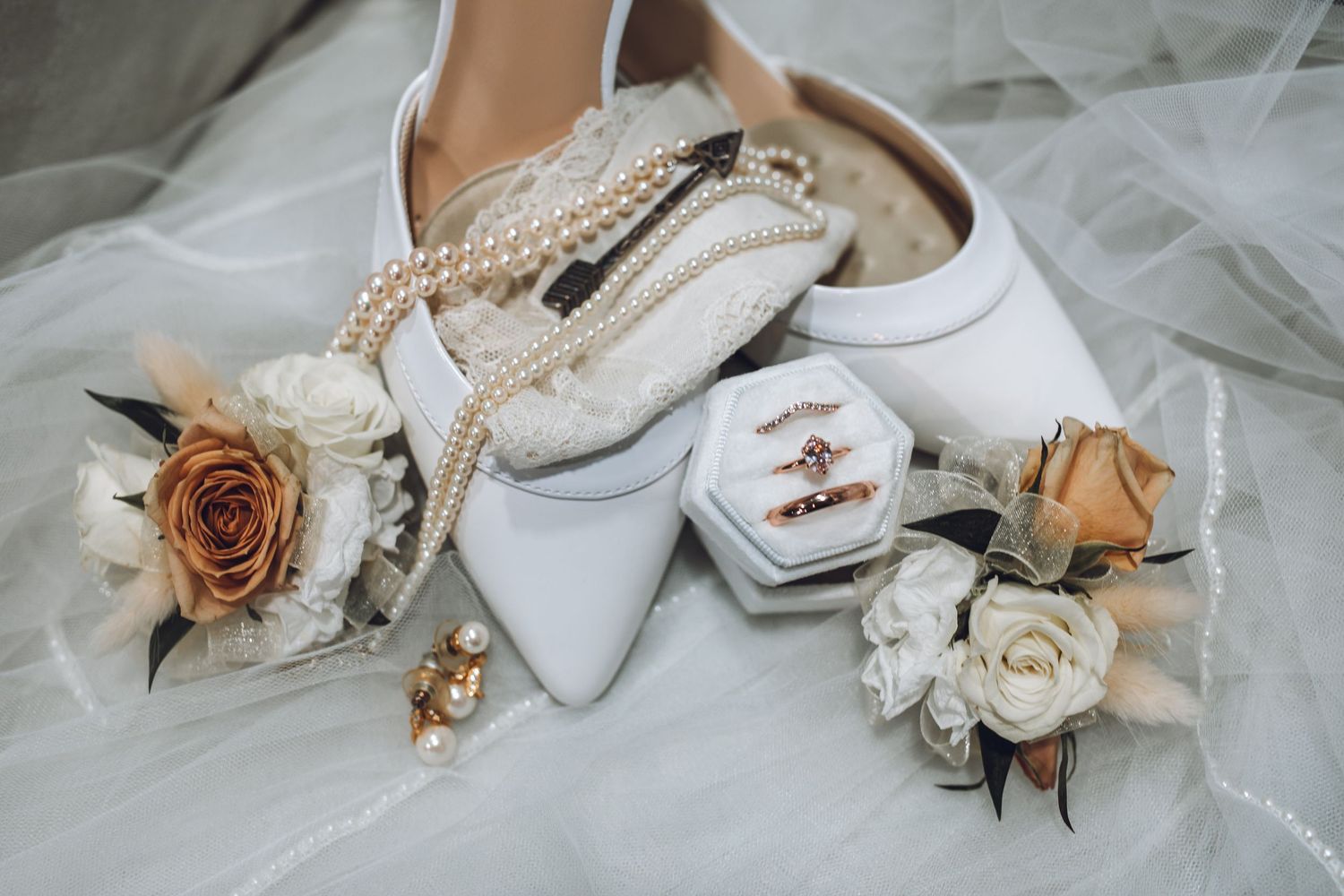 Wedding accessories including white shoes, pearls, and dried flowers arranged artistically.