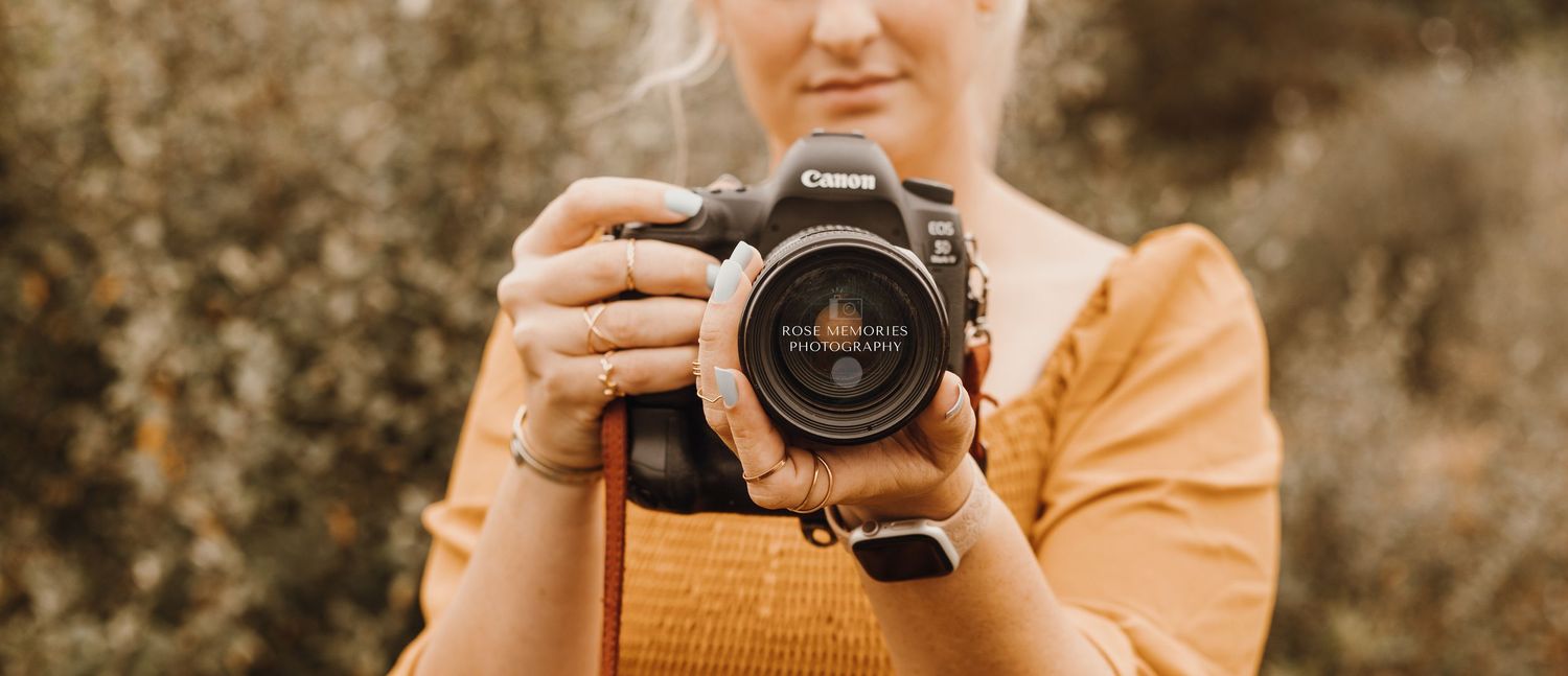 Photographer holding professional camera with orange tinted background.