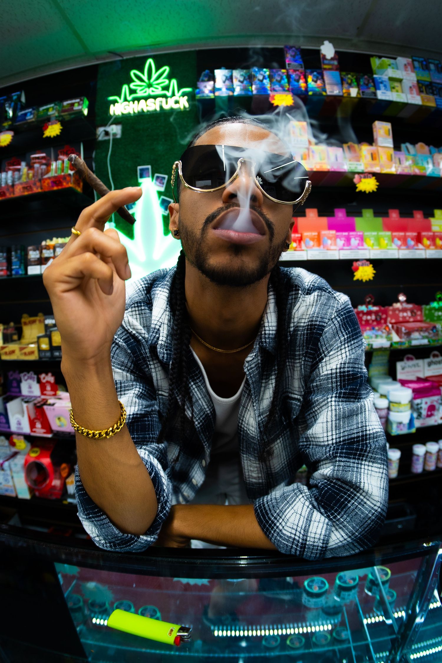 Man smoking cigar in sunglasses behind smoke shop counter.