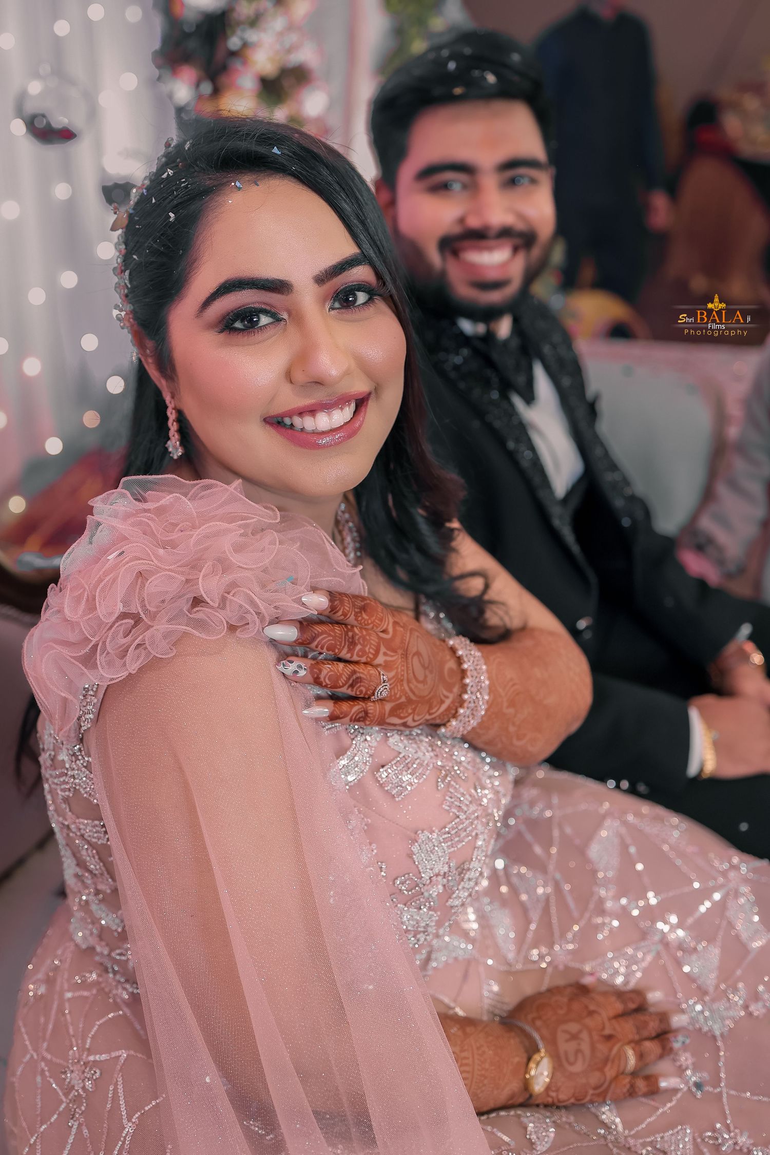 Candid wedding moment captured with soft bokeh lights and pink floral details.