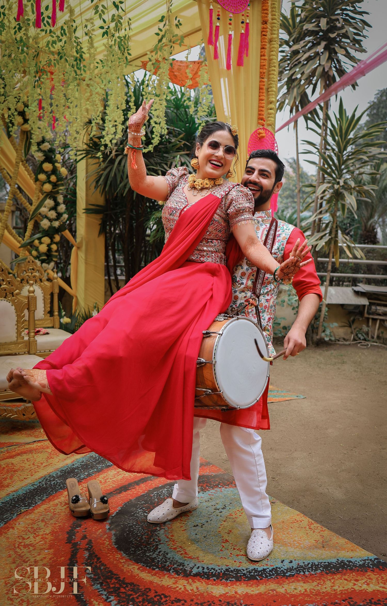 A couple in traditional Indian wedding attire dances together on a decorated outdoor patio during a celebration.