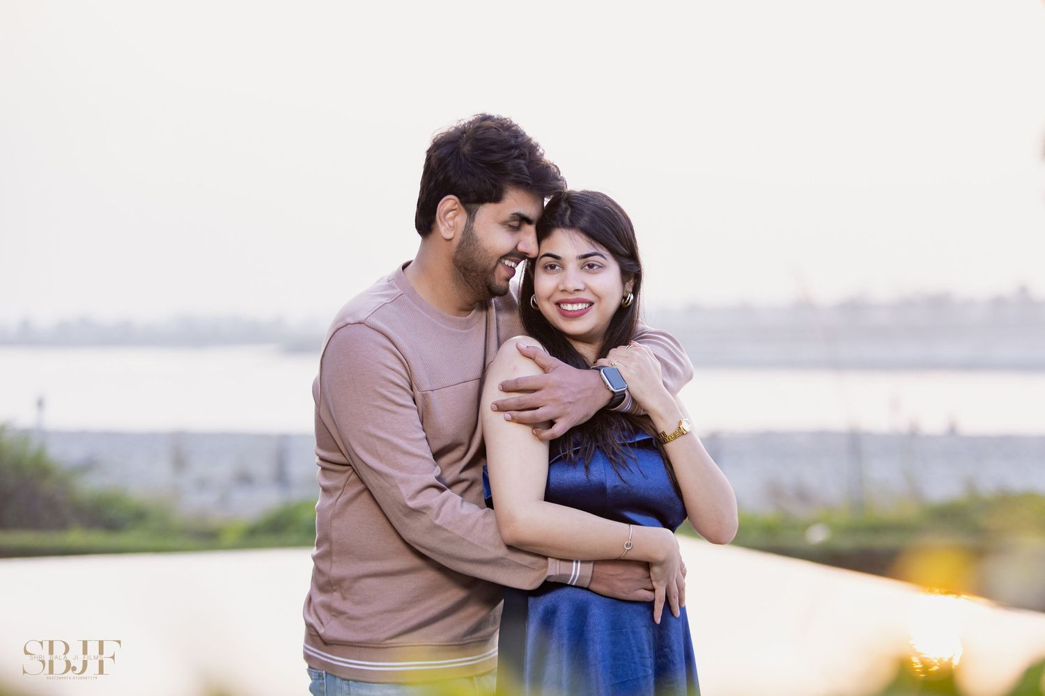 A couple shares a tender embrace outdoors against a scenic natural backdrop during a photo session.