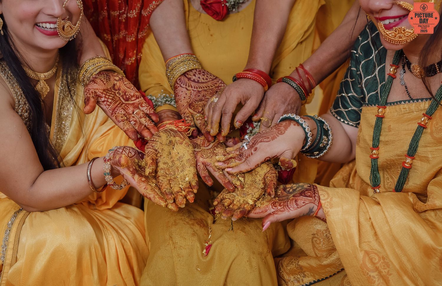 Women in traditional Indian attire display intricate mehndi henna designs on their hands during a wedding celebration.