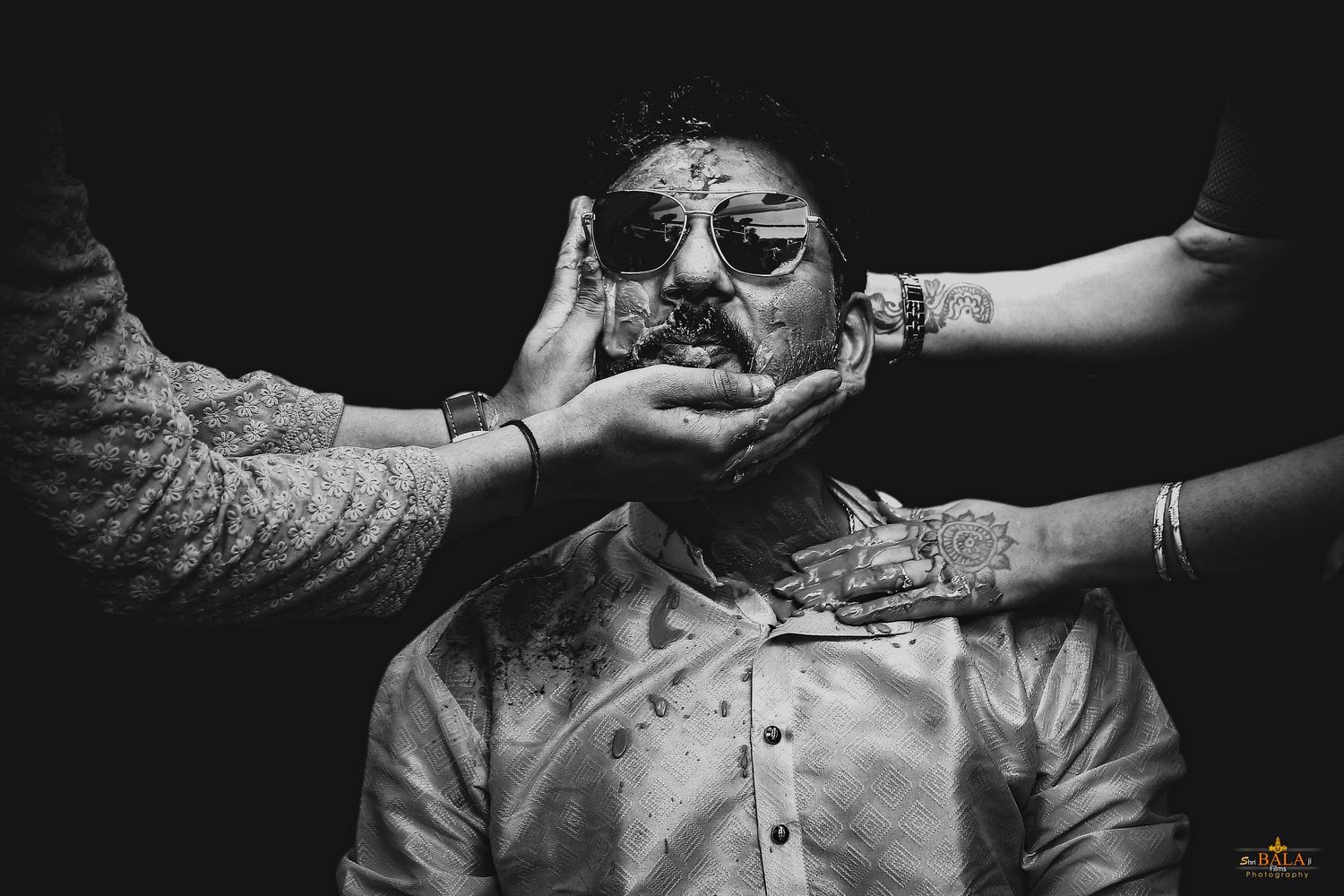 Black and white photo showing hands applying turmeric during an Indian wedding ritual.