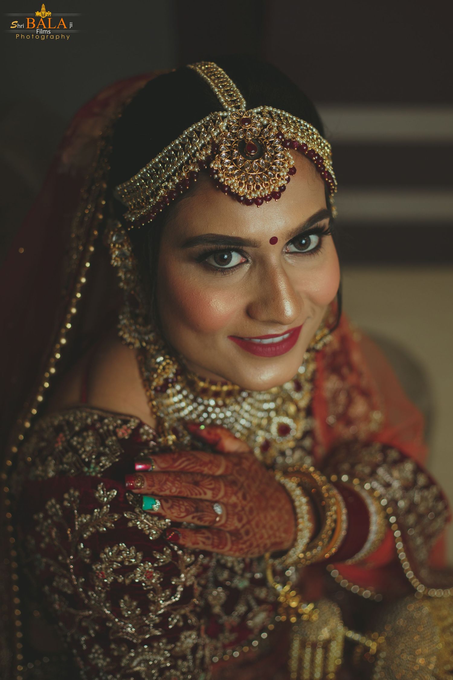 Traditional Indian bridal look featuring intricate gold jewelry and mehndi adorned hands.