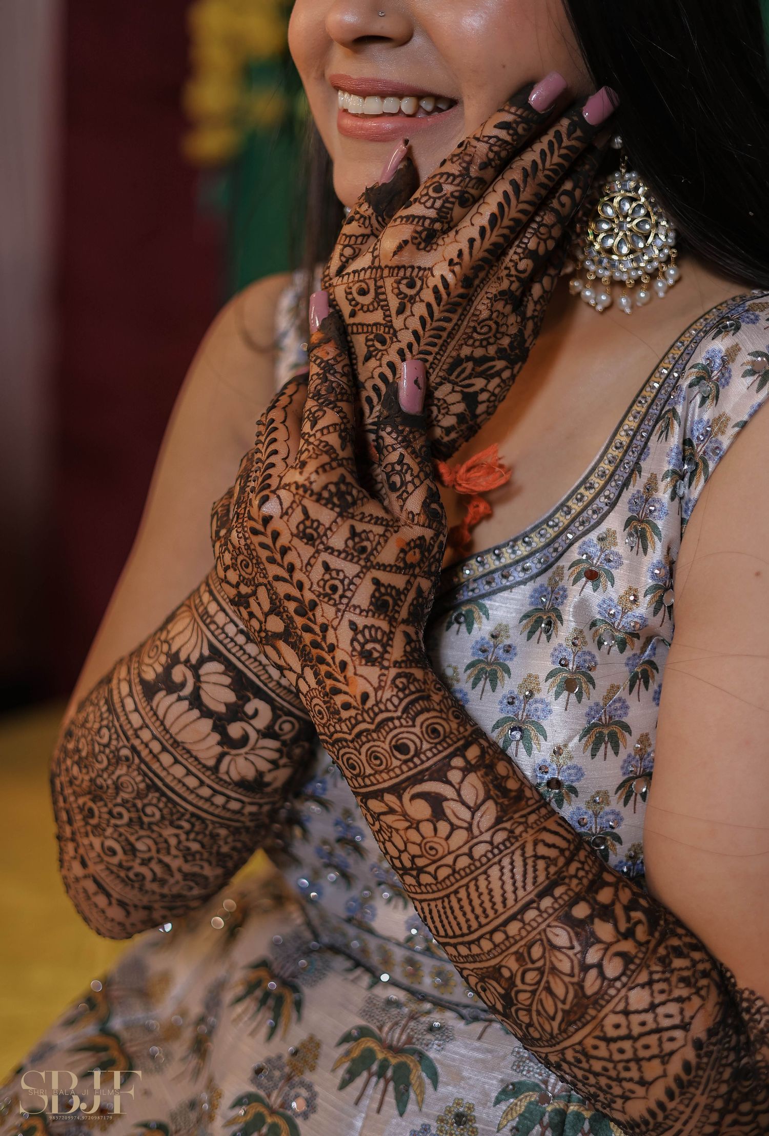 Intricate bridal mehndi design displayed on hands with ornate floral patterns and traditional Indian jewelry visible.