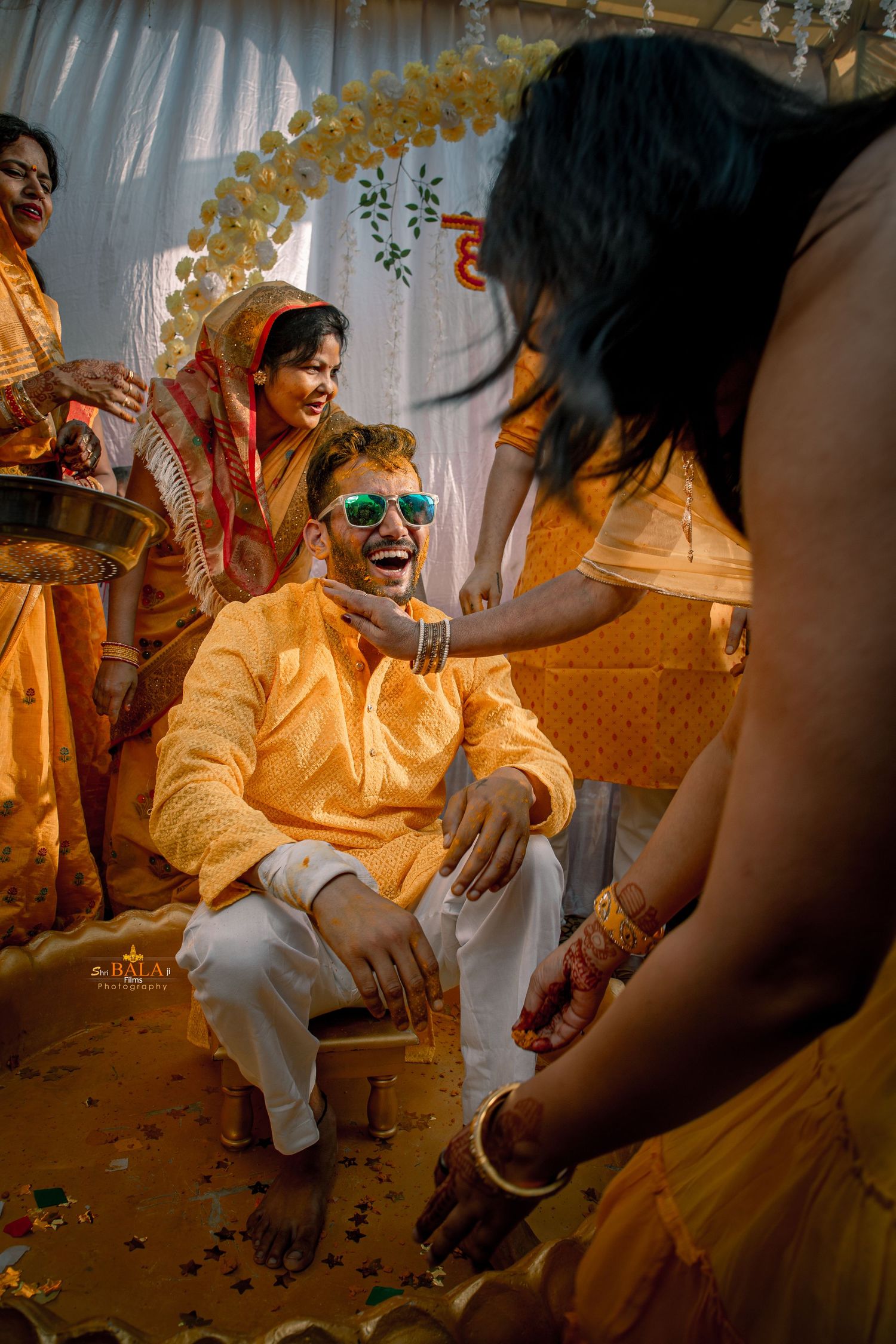 Festive Indian pre-wedding ceremony with yellow decor and traditional attire.