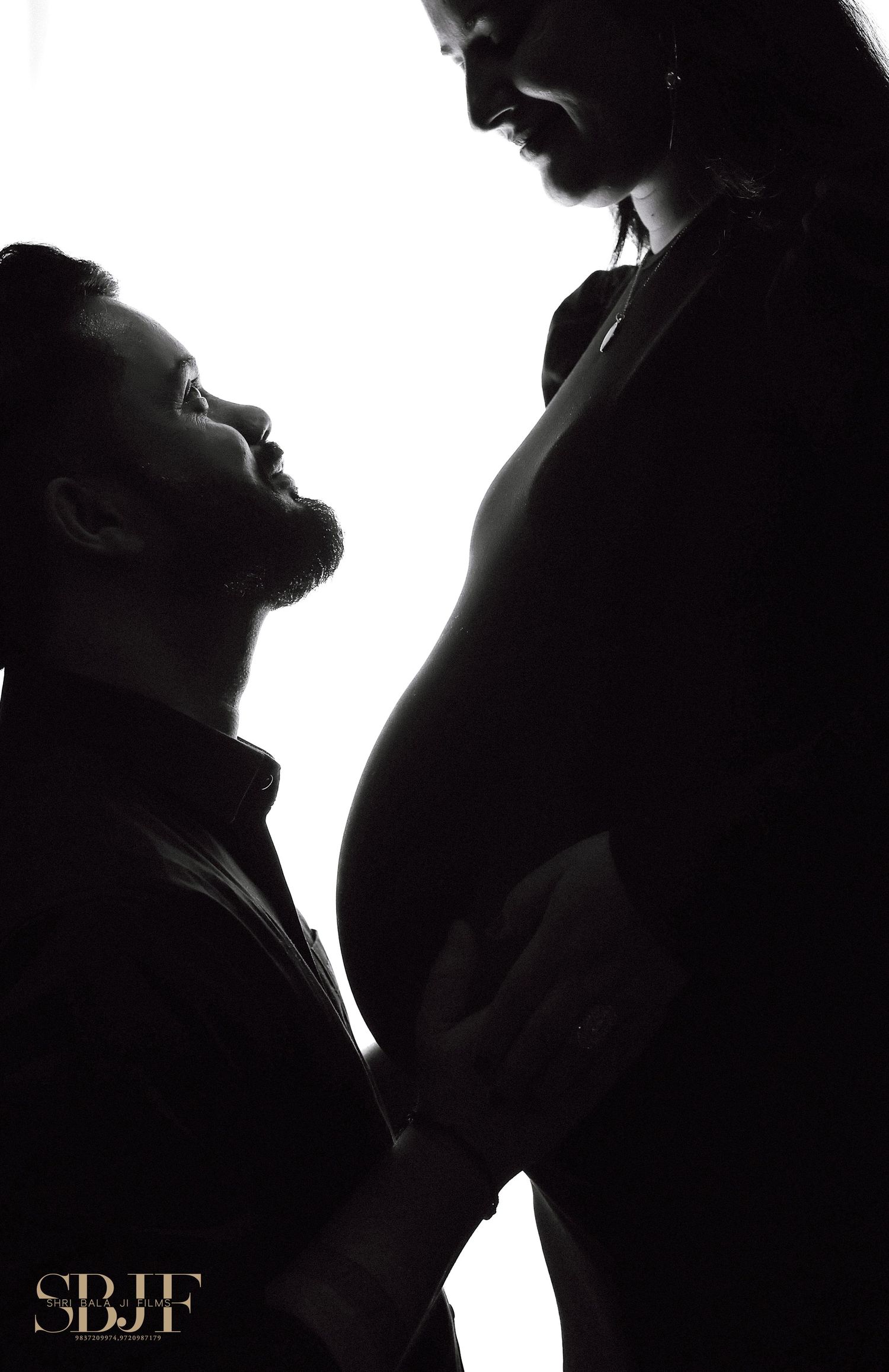 Artistic silhouette of expecting couple in intimate black and white portrait.