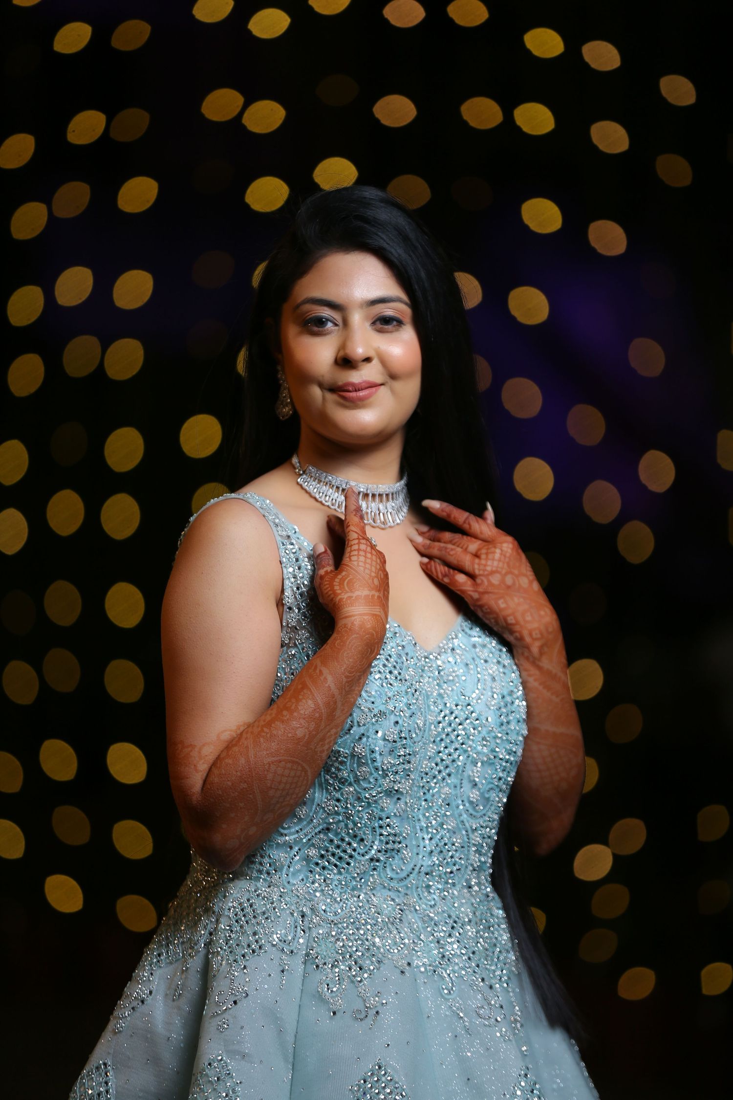 A glamorous portrait with bokeh lights featuring a sparkly blue evening gown.