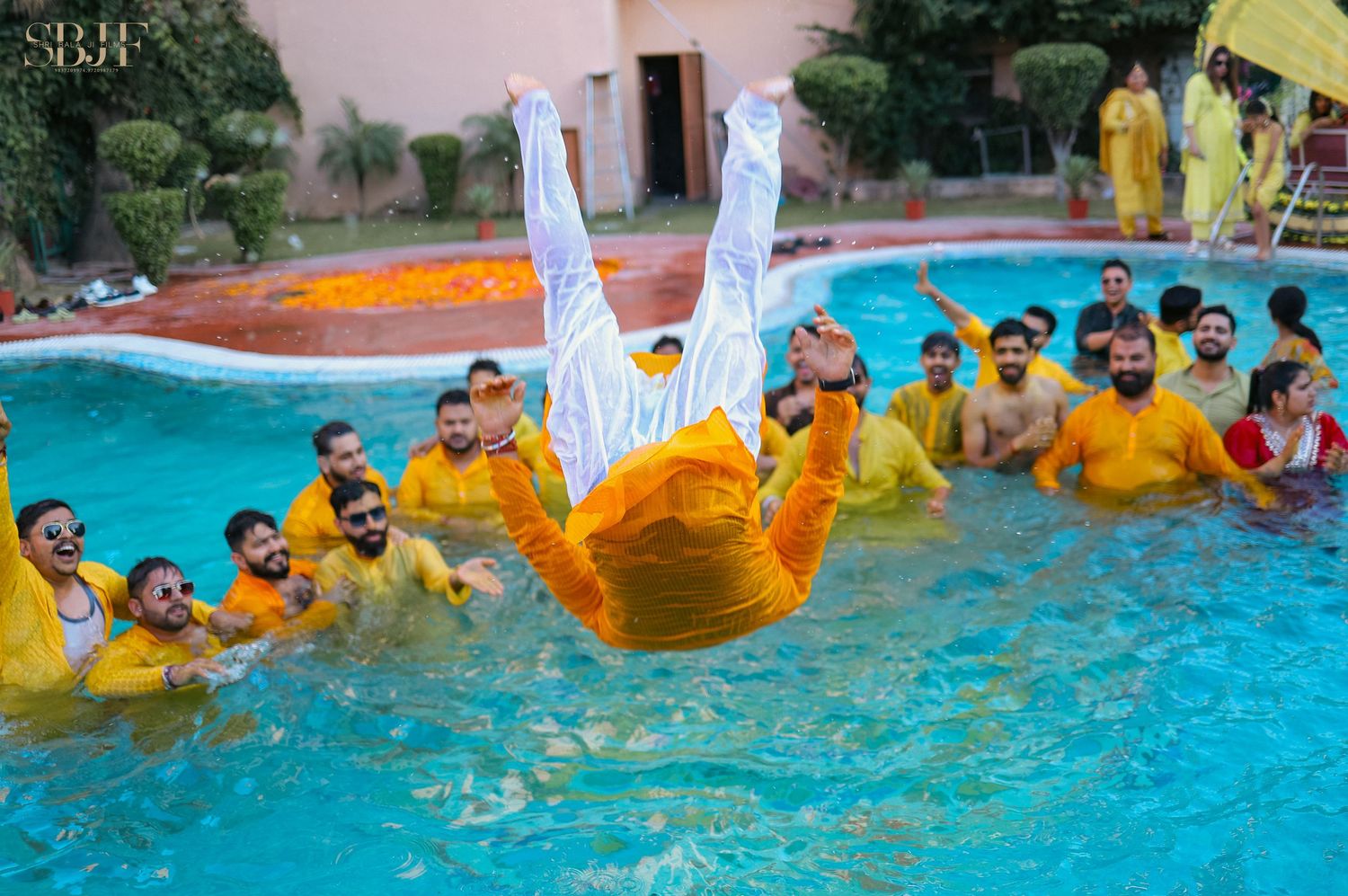 A group of people enjoy playing in a bright blue swimming pool with yellow inflatable tubes during a fun summer activity.