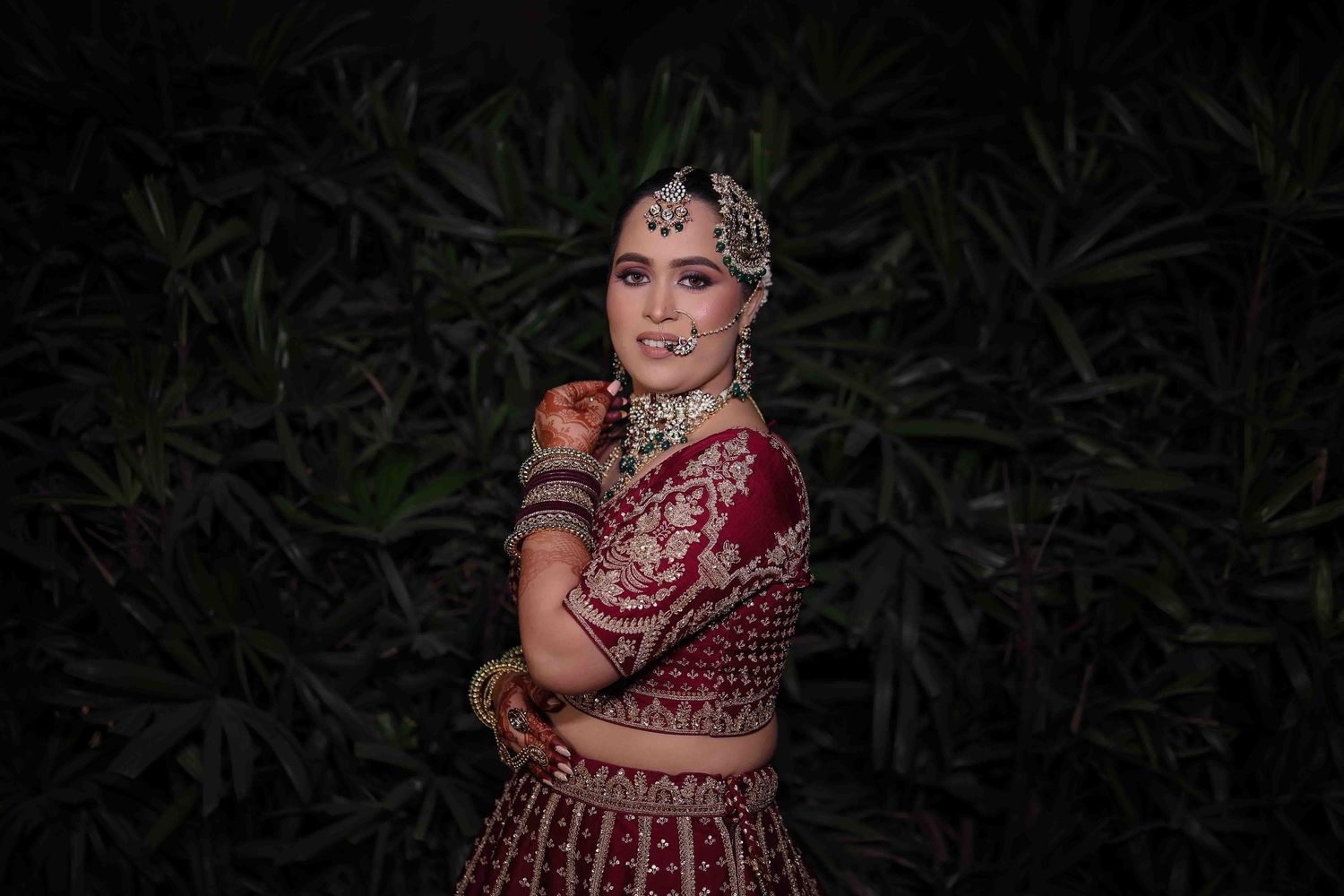 A series of photos showing someone in a traditional red and gold Indian wedding lehenga against a dark background.