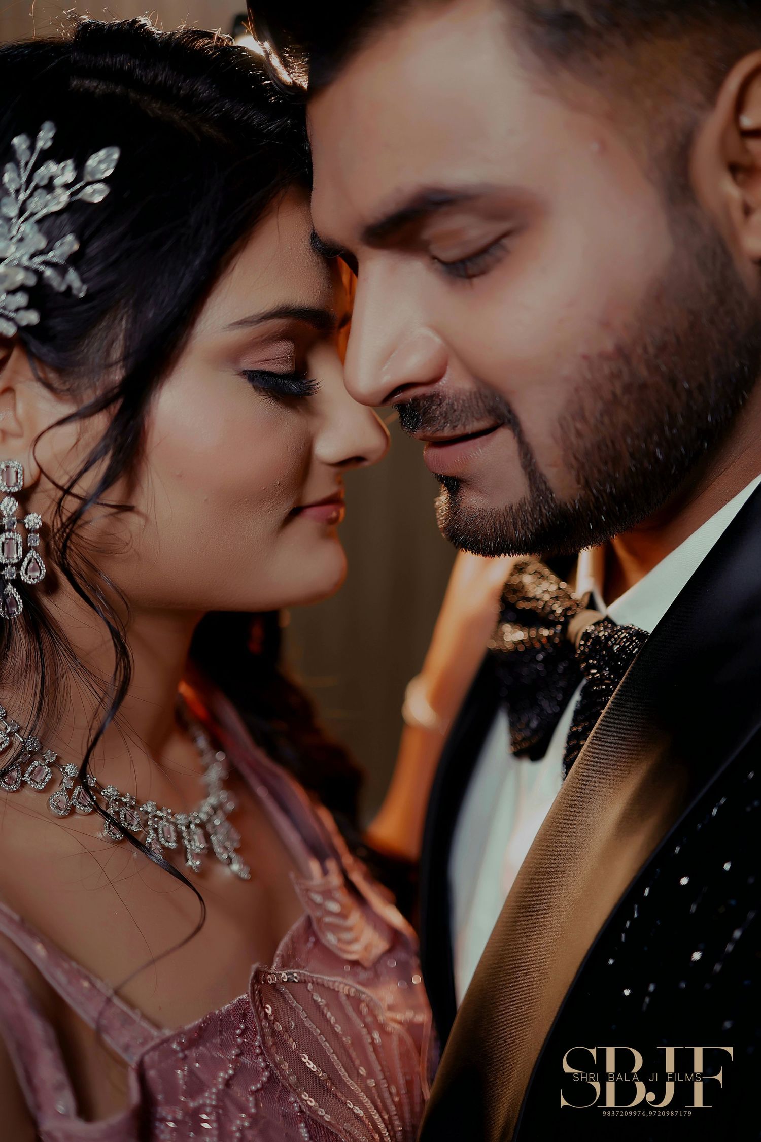 A romantic close-up wedding portrait showing a couple in formal attire with jewelry and bow tie in warm lighting.
