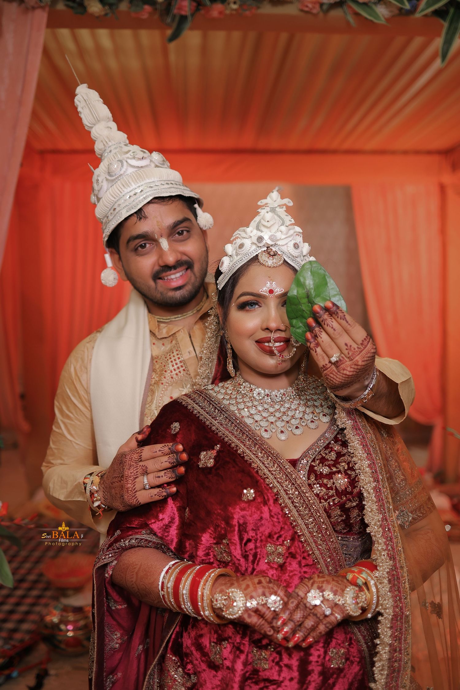 Traditional Bengali wedding couple in ceremonial attire with unique silver crowns.