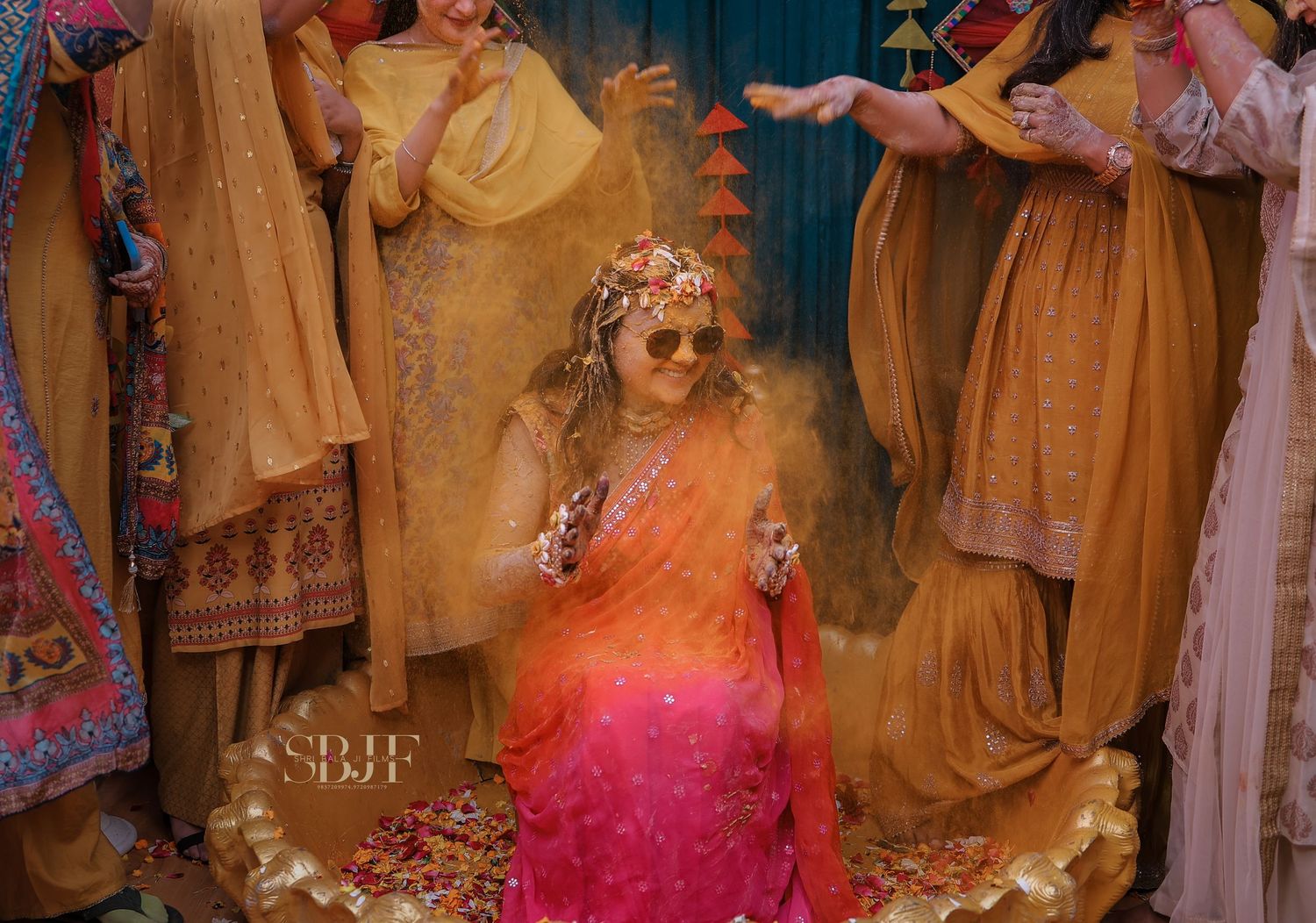 Traditional Indian wedding ceremony with bride in pink and gold lehenga surrounded by family members during rituals.
