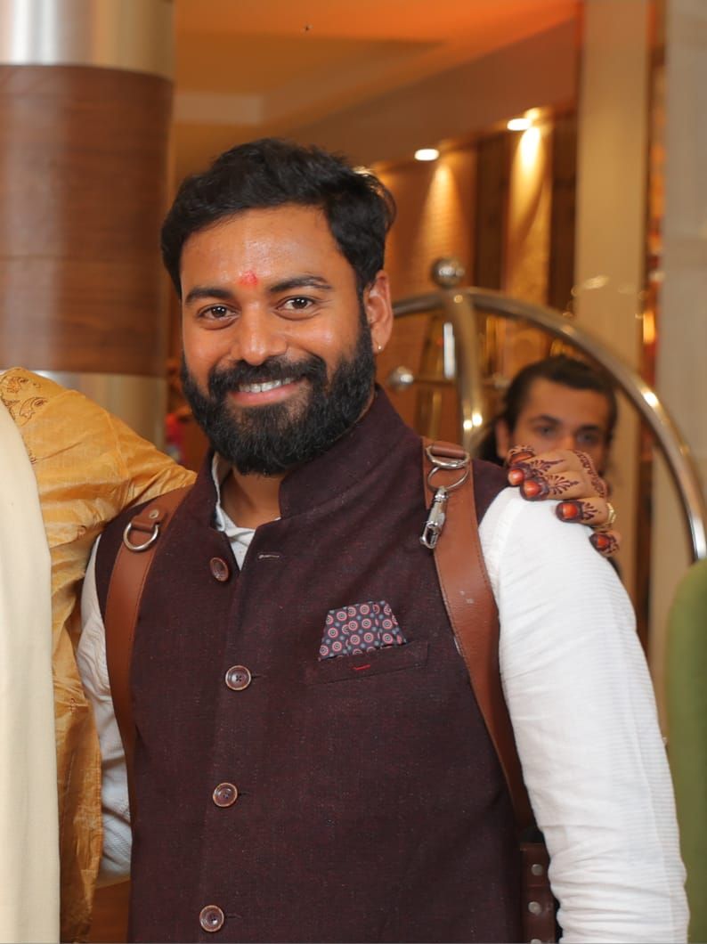 People in formal attire gathered indoors for an event, wearing brown and white outfits.