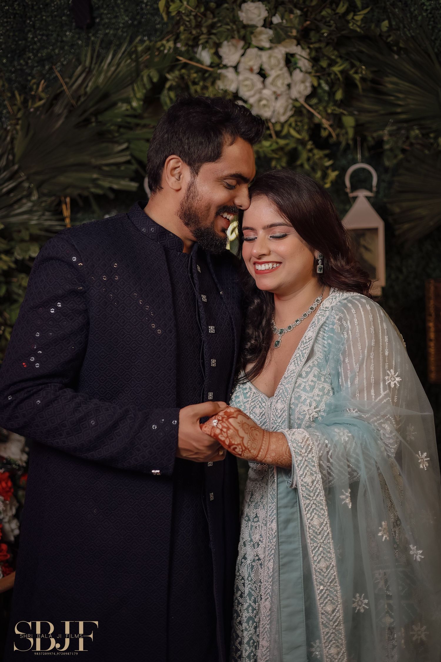 A couple shares romantic moments in traditional South Asian attire against a dark outdoor setting.