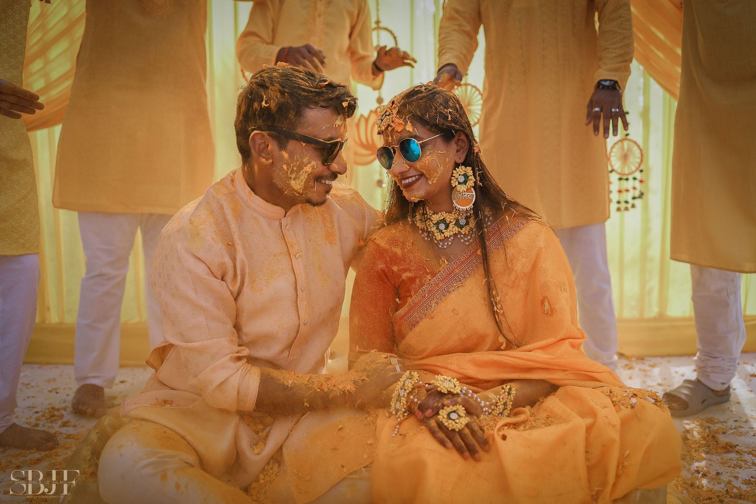 A couple covered in orange powder celebrates Holi festival with joyful expressions and traditional attire.