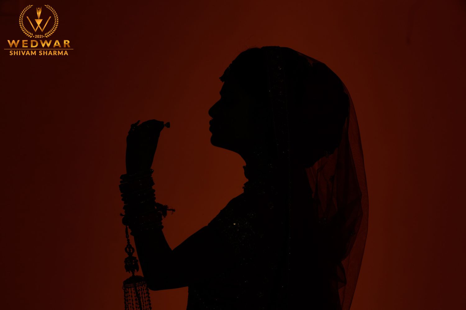 Silhouette of a bride in profile against a warm orange background, captured by Wedwar Shivam Sharma photography.