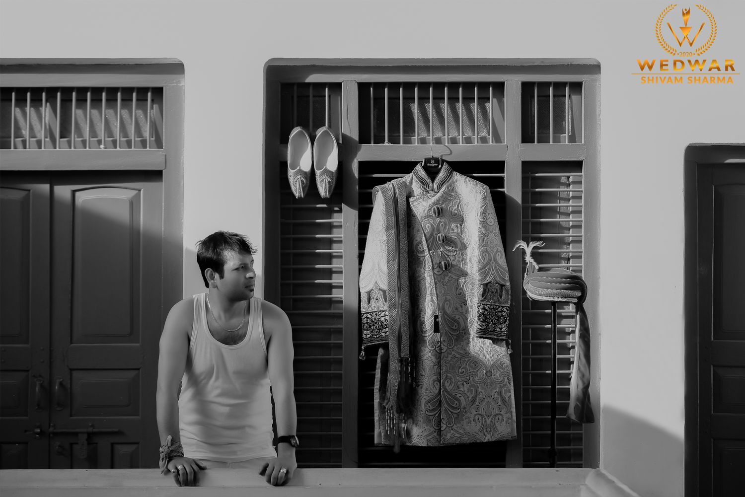 Black and white image of wedding attire hanging in wooden wardrobe.